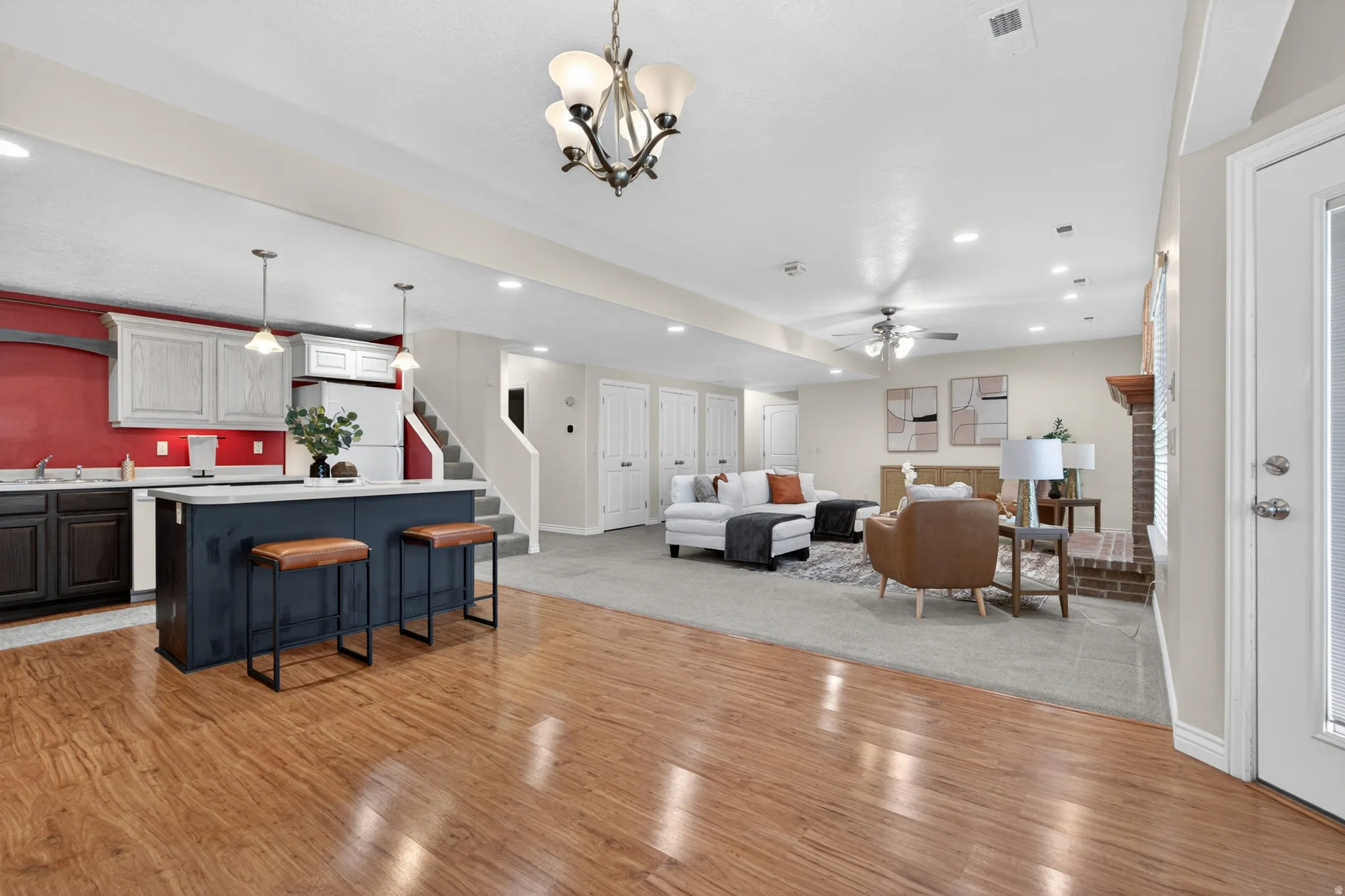 Expansive lower level featuring wood-finish flooring, a full kitchen with a central island, recessed lighting, a ceiling fan, and a brick fireplace