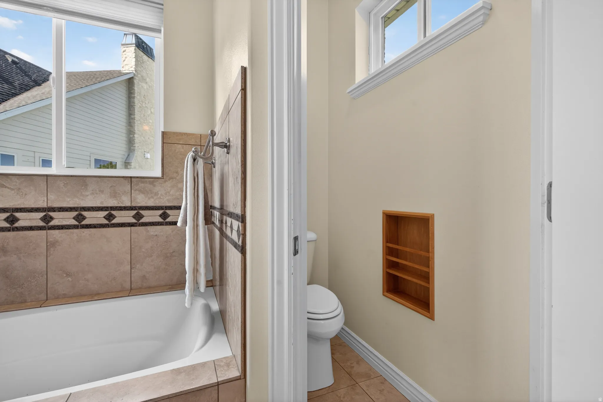 Bathtub with tiled surround featuring a decorative border