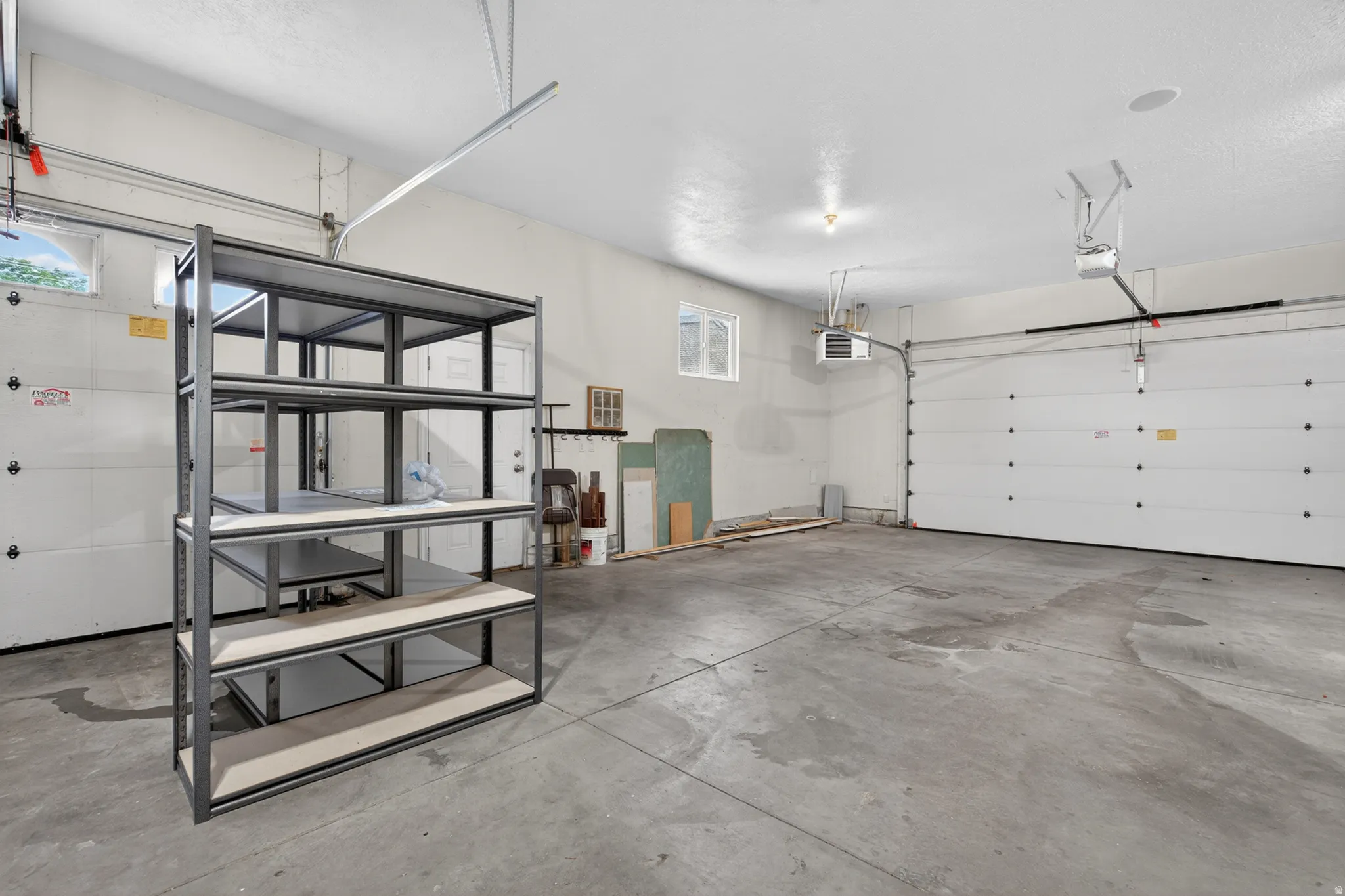 Spacious garage featuring two overhead doors, a concrete floor, and overhead lighting