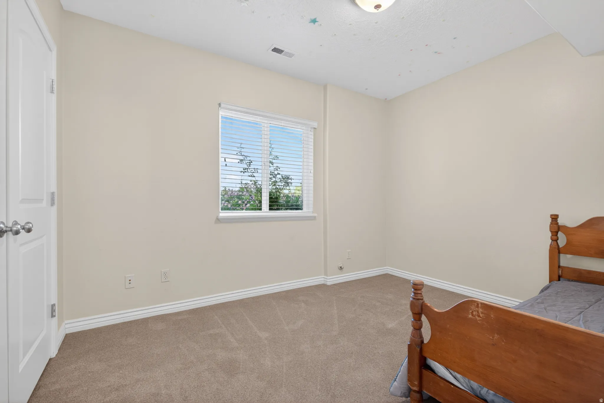 Carpeted room featuring a double-pane window with blinds, a white two-panel door, and white baseboards