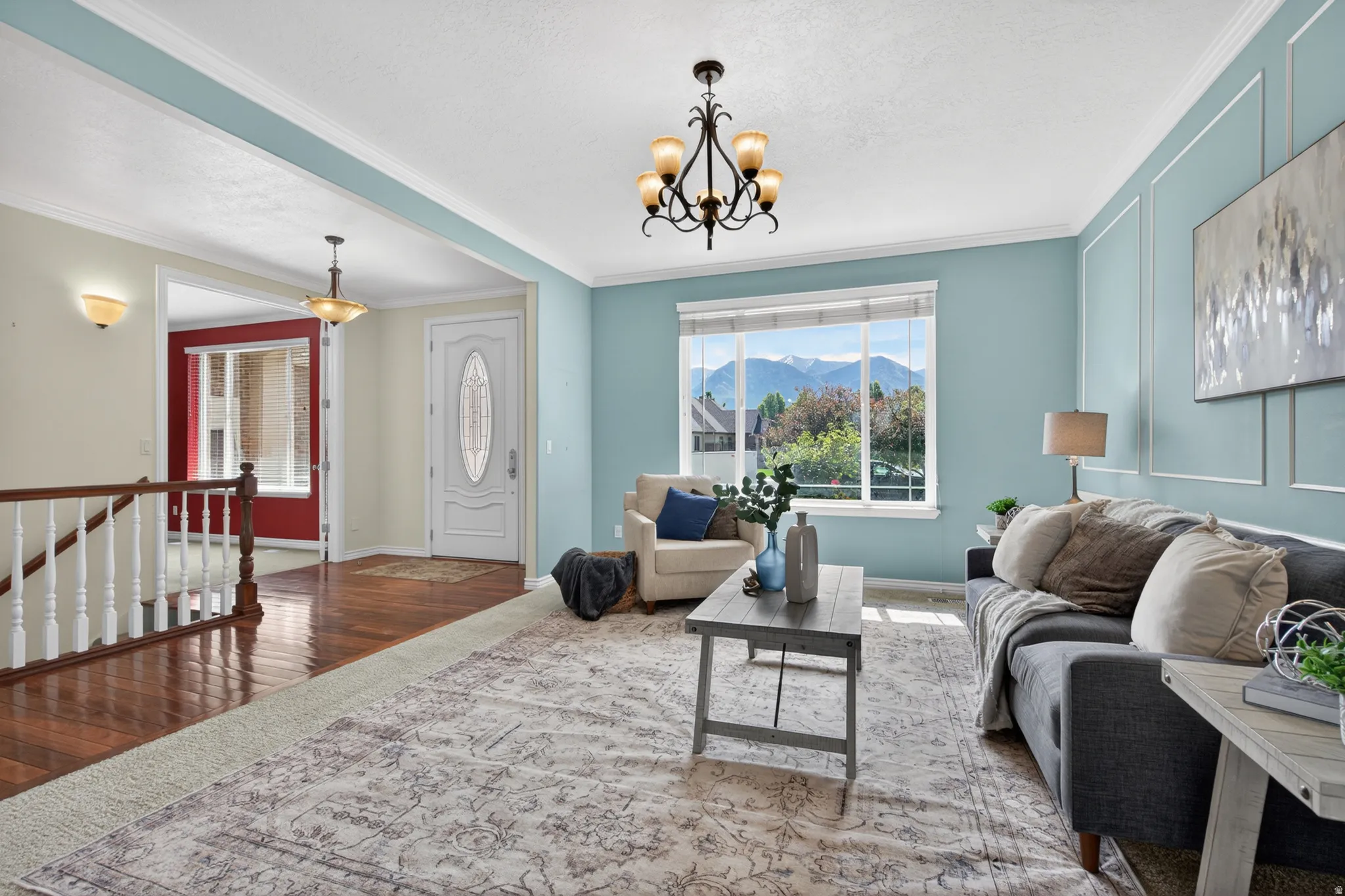 Front entry and living space featuring a decorative glass paneled door, wood-finish flooring, a chandelier, and a large window with mountain scenery