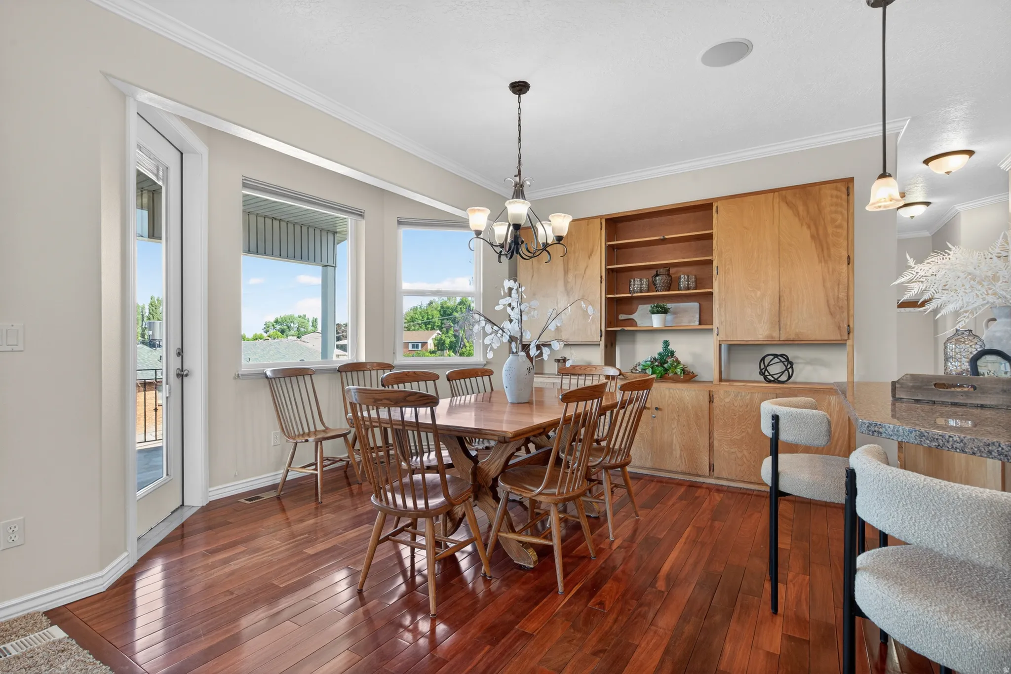 Dining area featuring wood-finish flooring, built-in cabinetry with open shelving, multiple windows, and a glass-paneled door