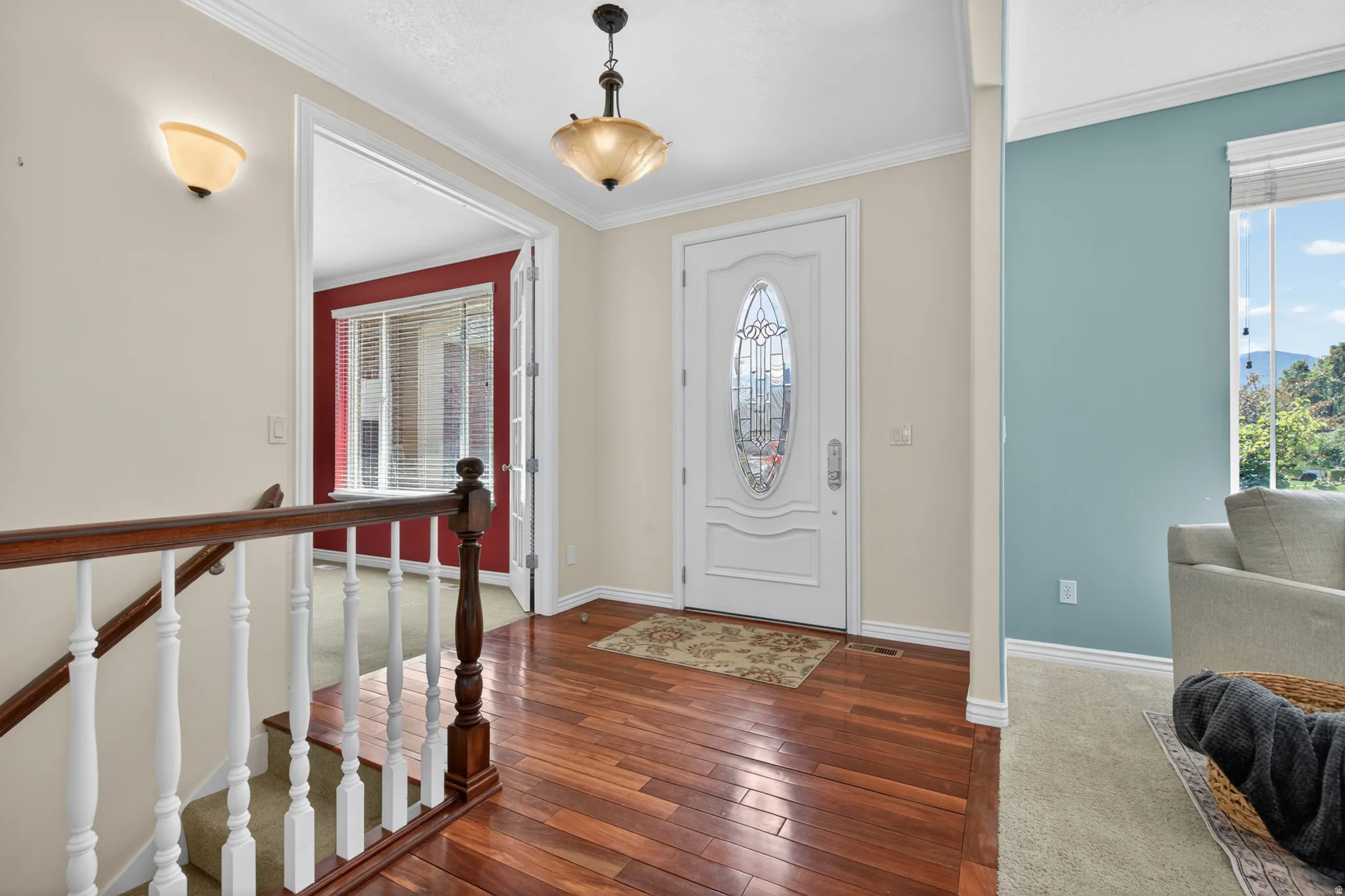 Entryway featuring wood-finish flooring, a white front door with decorative glass, and a traditional chandelier