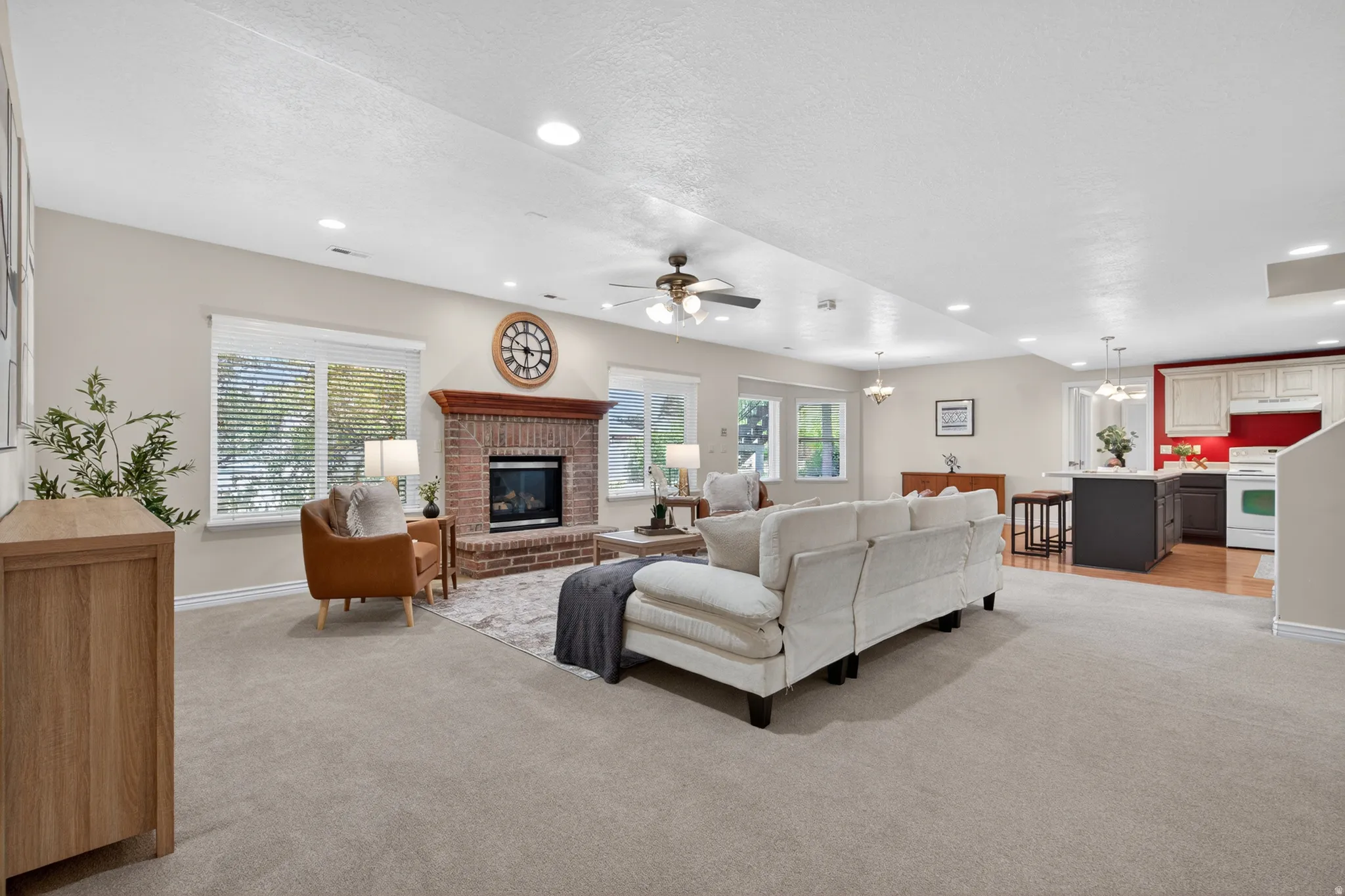 Open-concept living area featuring a brick fireplace with a wood mantle, recessed lighting, and a ceiling fan