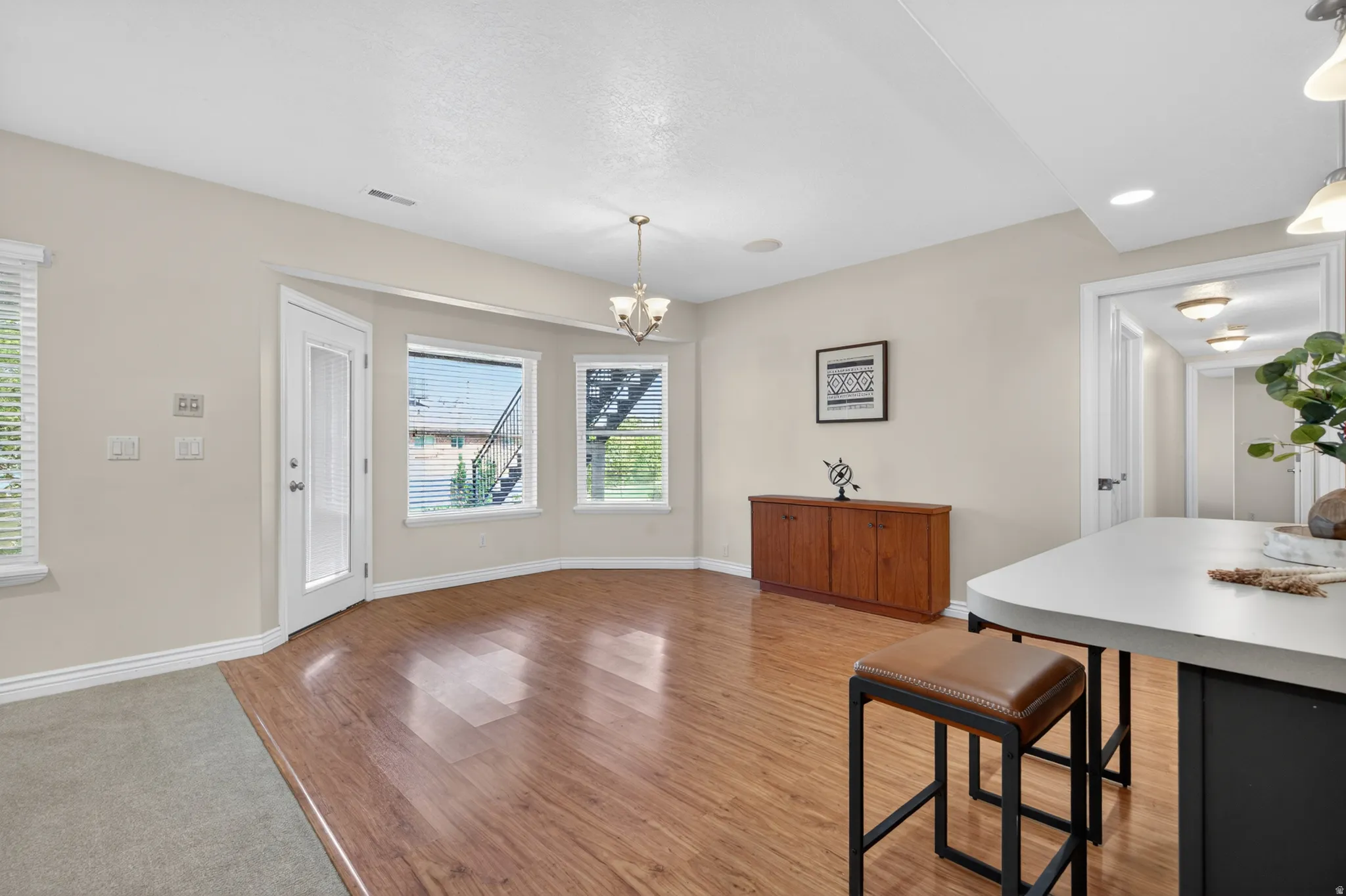 Open-concept living space with wood-finish flooring, recessed lighting, and a chandelier