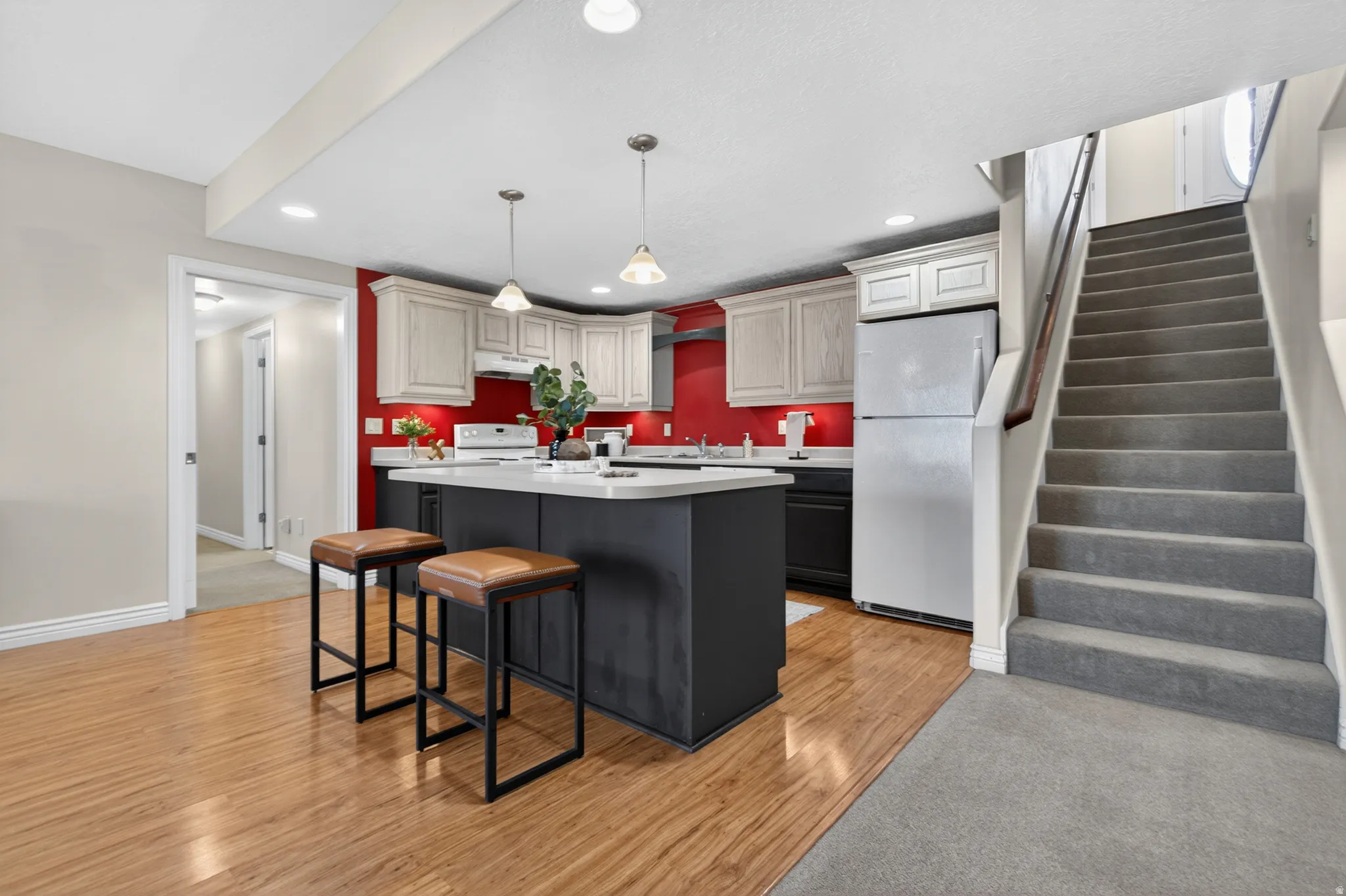Open-concept kitchen featuring an eat-at island, light-finish cabinetry, stainless steel appliances, and wood-finish flooring
