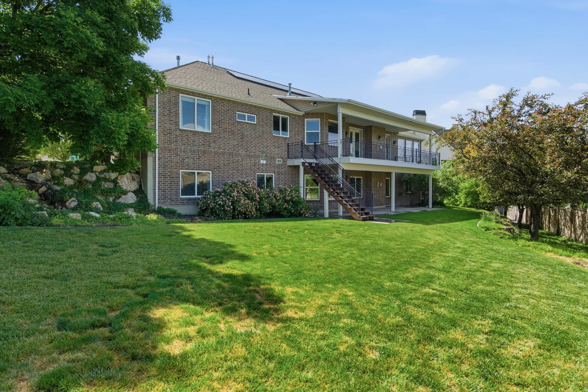 Expansive rear yard featuring a multi-level brick exterior and a substantial lawn area