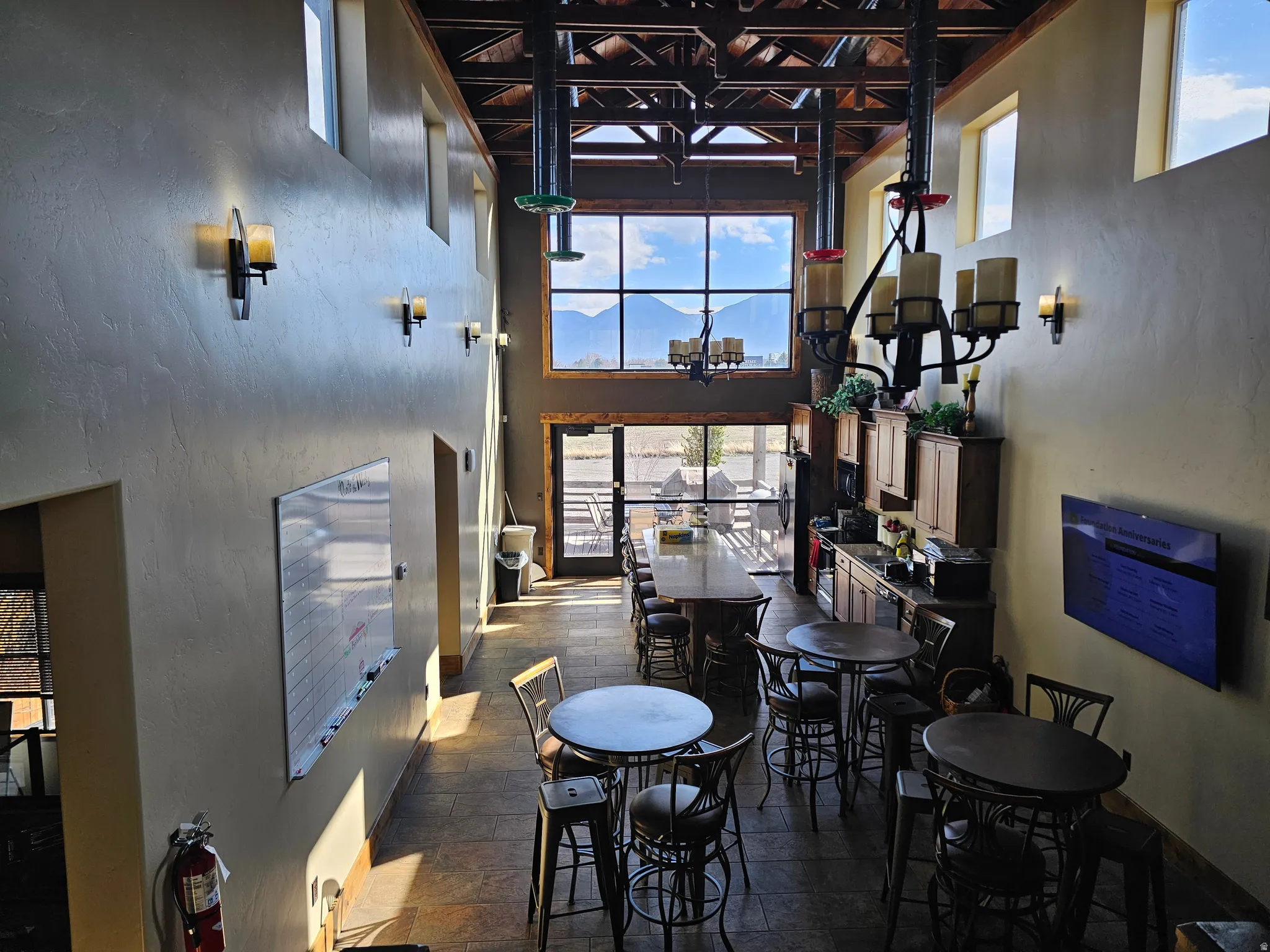 Two-story interior space featuring exposed wood beams, a two-story window wall with mountain scenery, and upper-level windows
