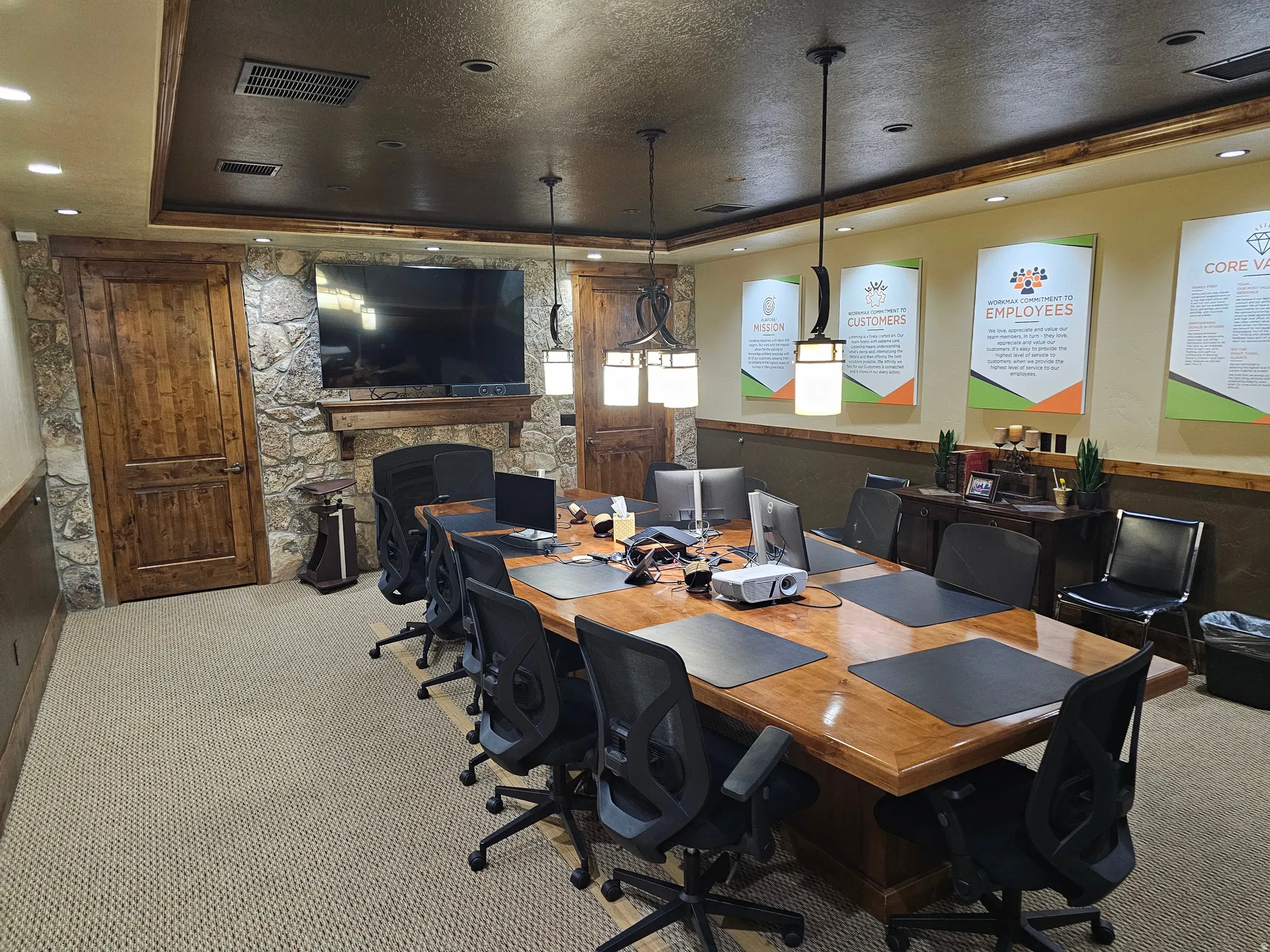 Conference room featuring a large wood-finish table, stone accent wall, recessed lighting, and suspended rectangular fixtures