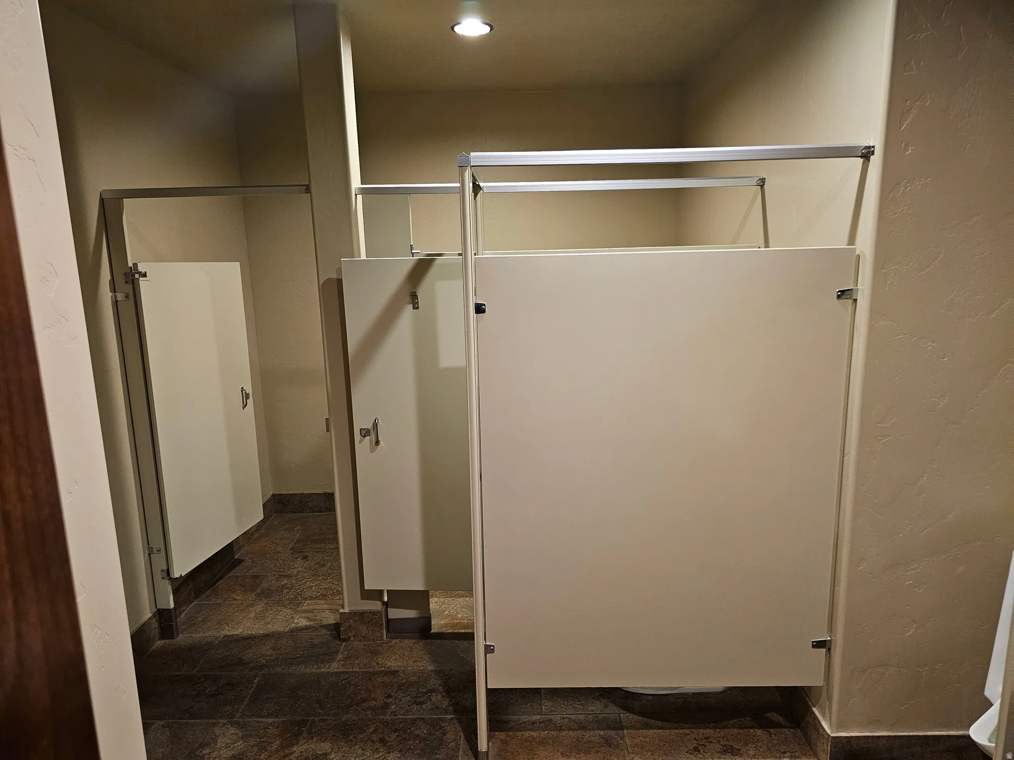 Multiple stalls with light-colored privacy panels and aluminum framing