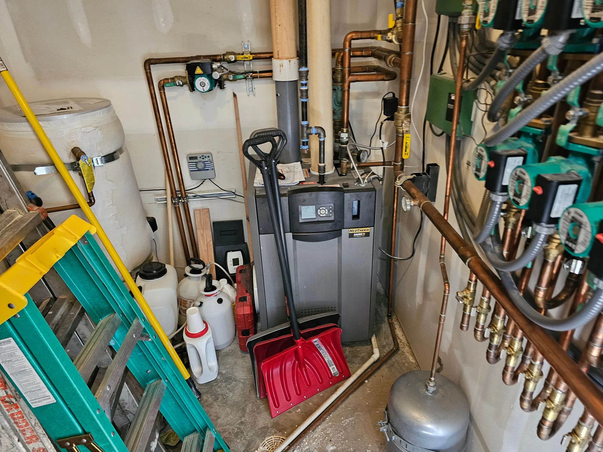 Mechanical room featuring a central heating unit with extensive copper plumbing, multiple circulation pumps, and an expansion tank