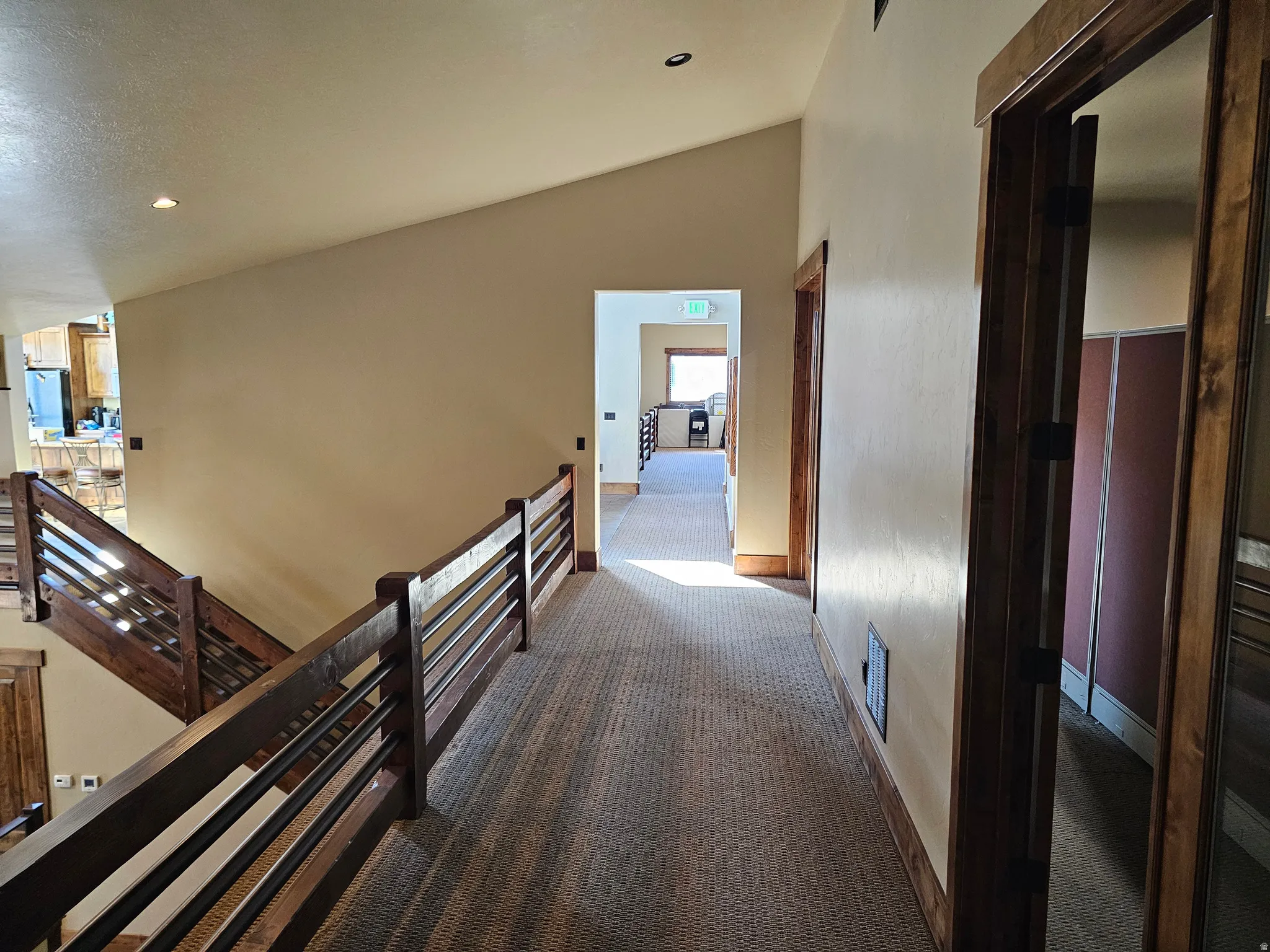 Upper-level hallway featuring textured carpet flooring, light-toned wall paint, and wood trim detailing