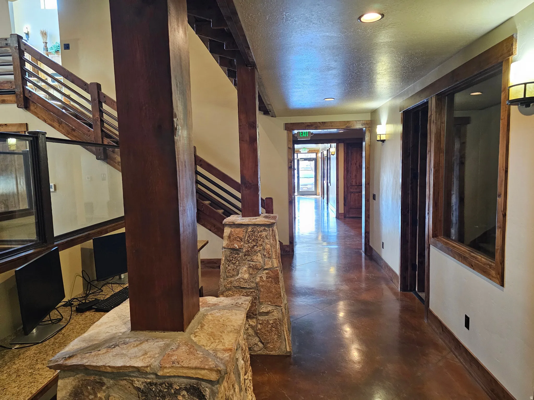 Spacious interior hallway featuring rich wood-finish trim, exposed wood beams, and natural stone accents