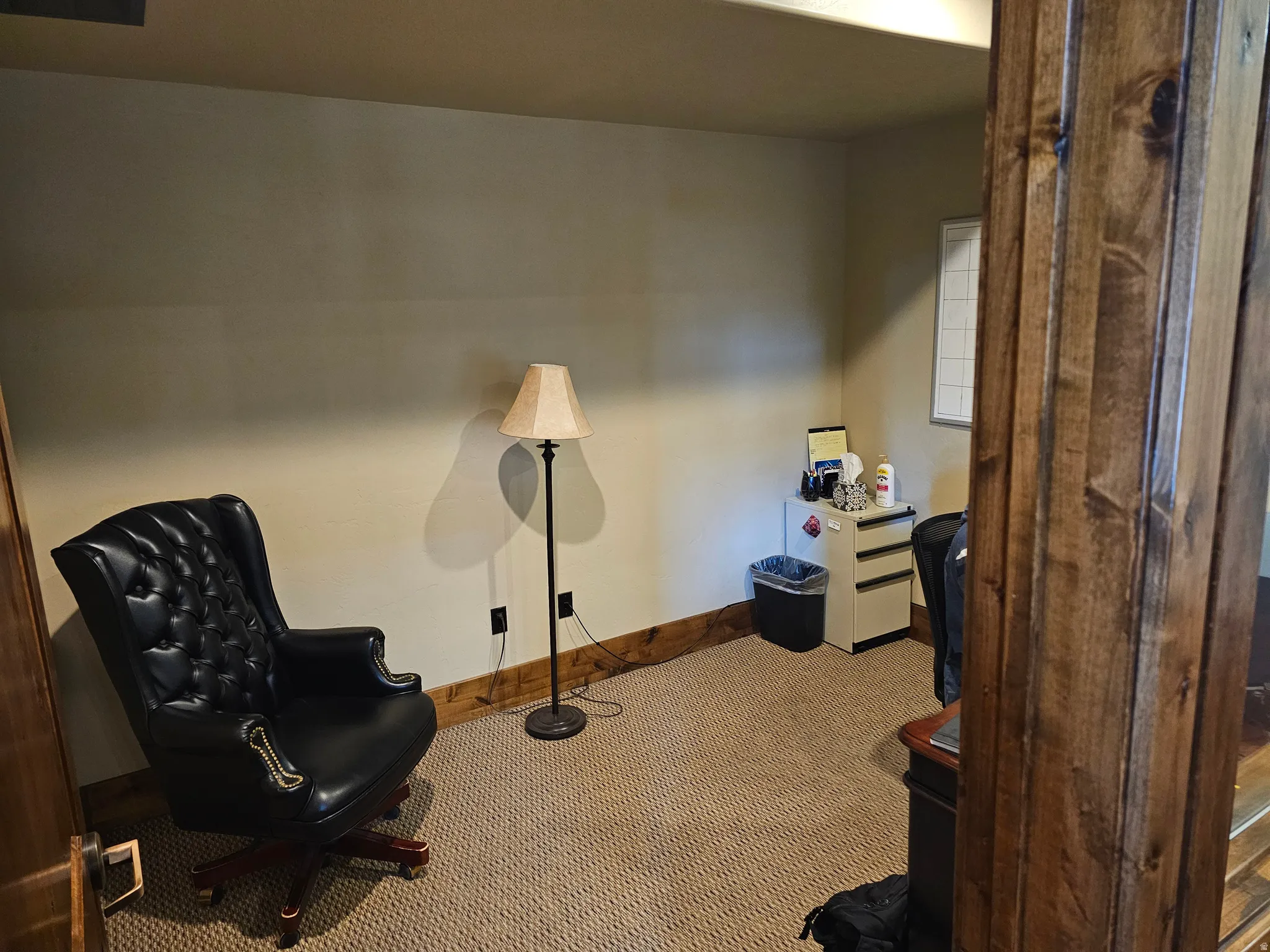 Carpeted room with a wooden baseboard trim and wood-paneled door frame