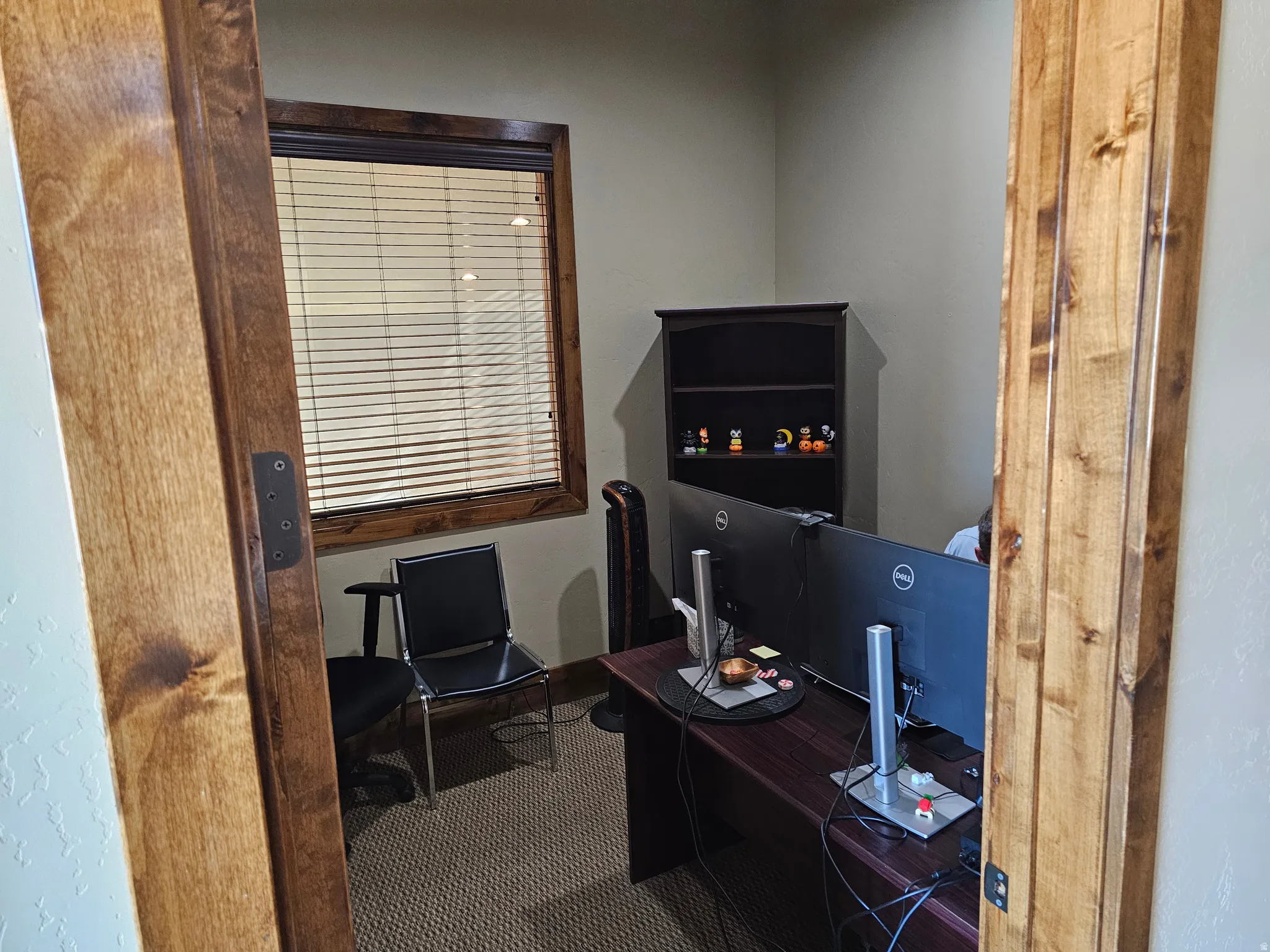 Carpeted room featuring a window with horizontal blinds, wood-finish trim, and light beige walls