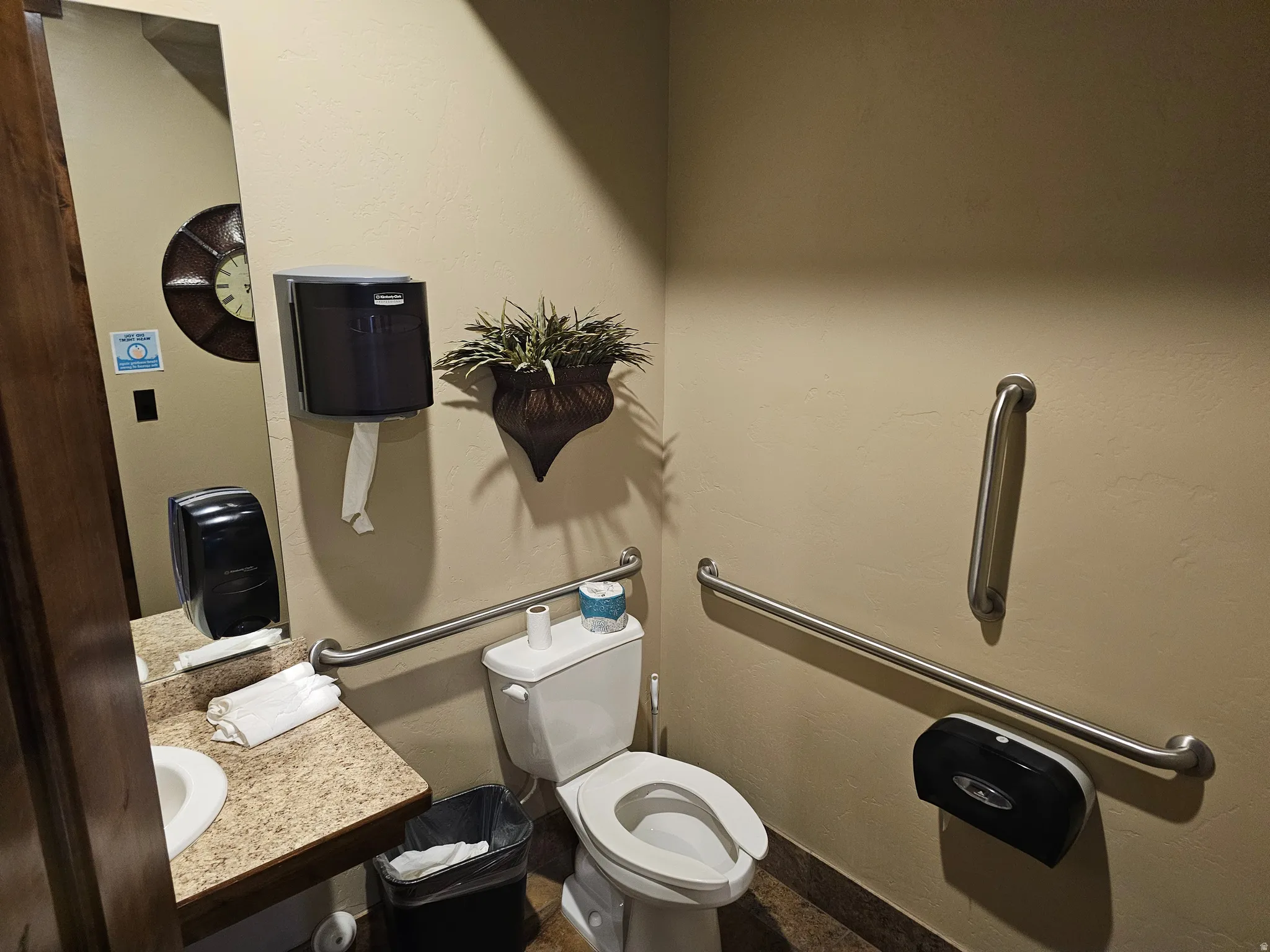 Restroom featuring a neutral color palette, speckled vanity countertop, and grab bars