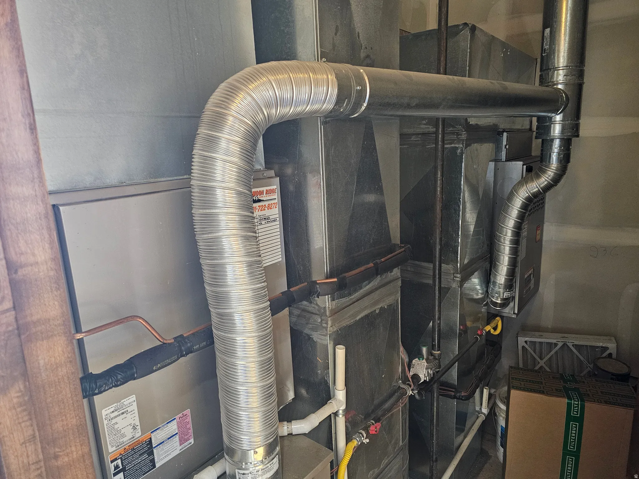 Utility area featuring a forced-air furnace, interconnected ductwork, and visible copper piping