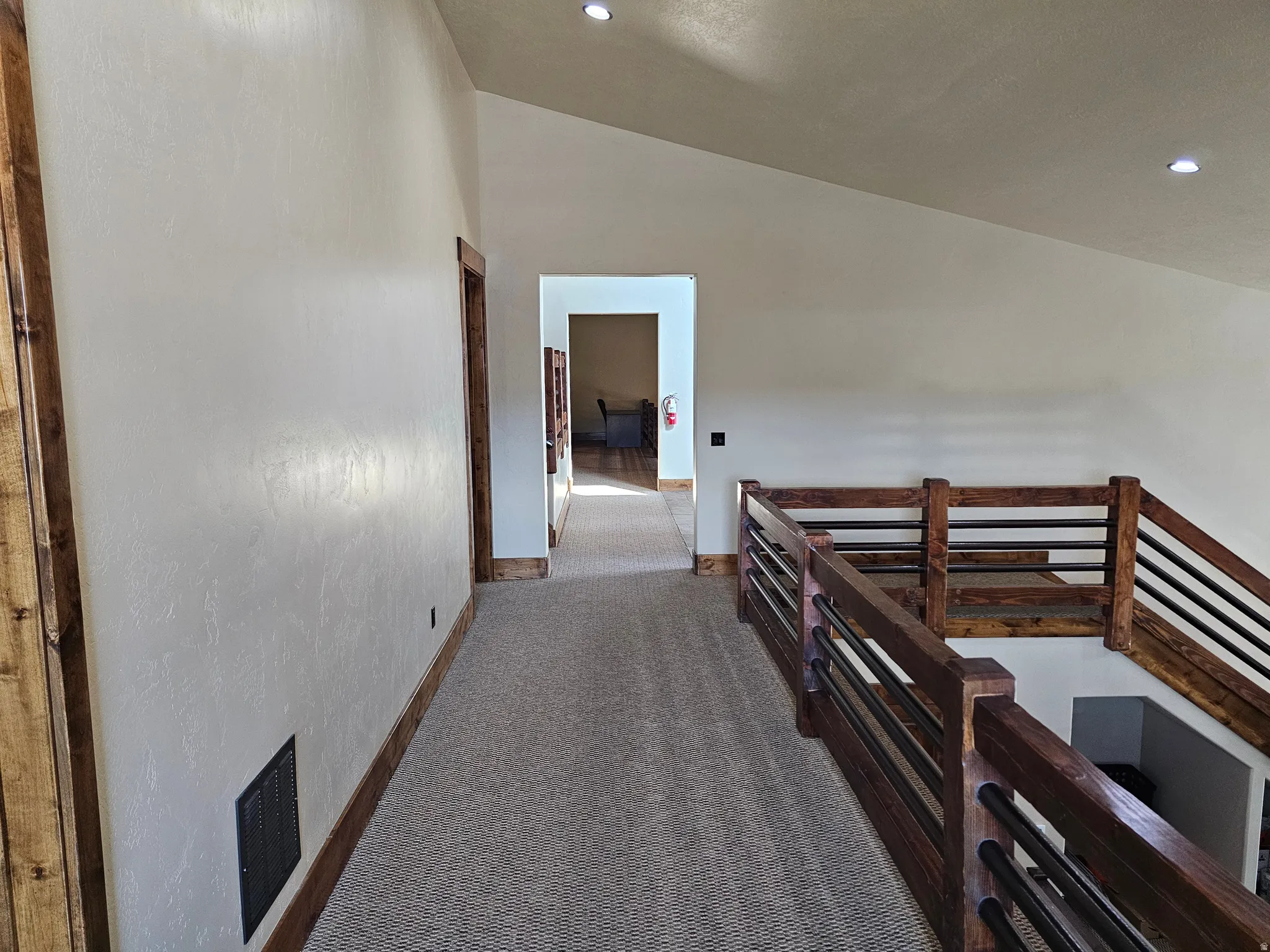 Upper-level hallway featuring textured walls and recessed lighting