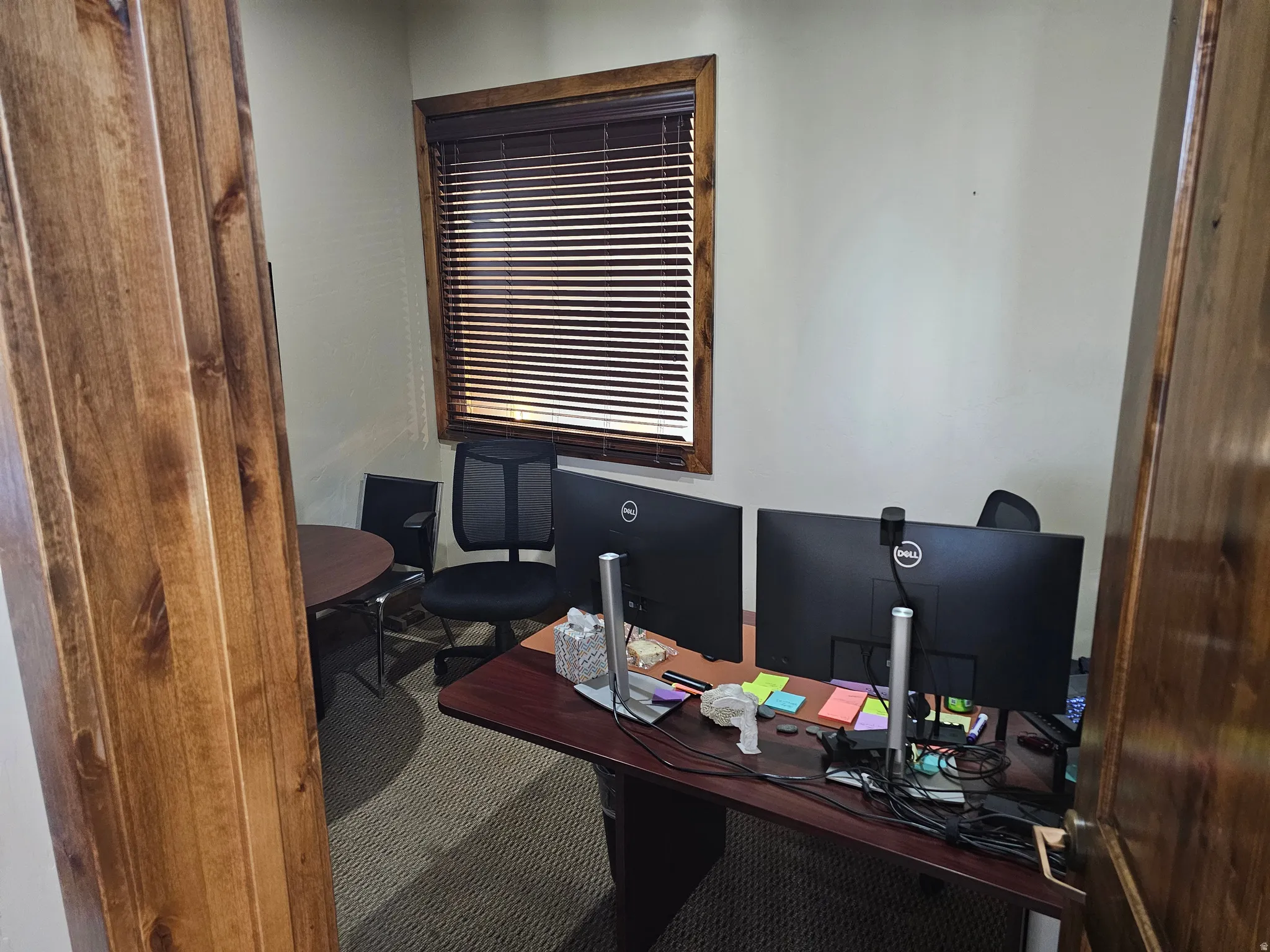 Compact room featuring light-toned walls and wood-finish trim around a window with horizontal blinds