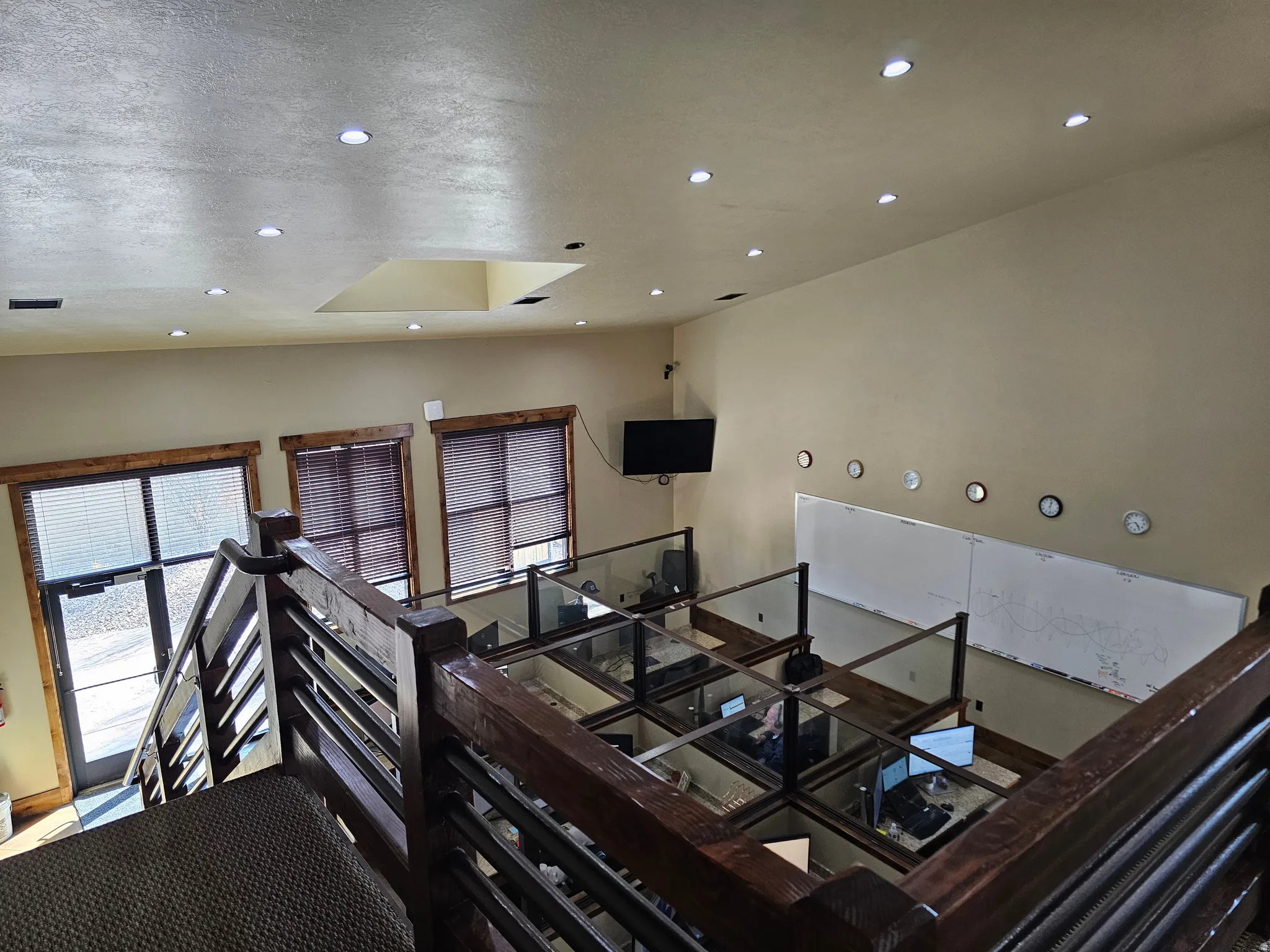 Upper-level space featuring a wood-finish railing with horizontal balusters, recessed lighting, and a light-colored ceiling