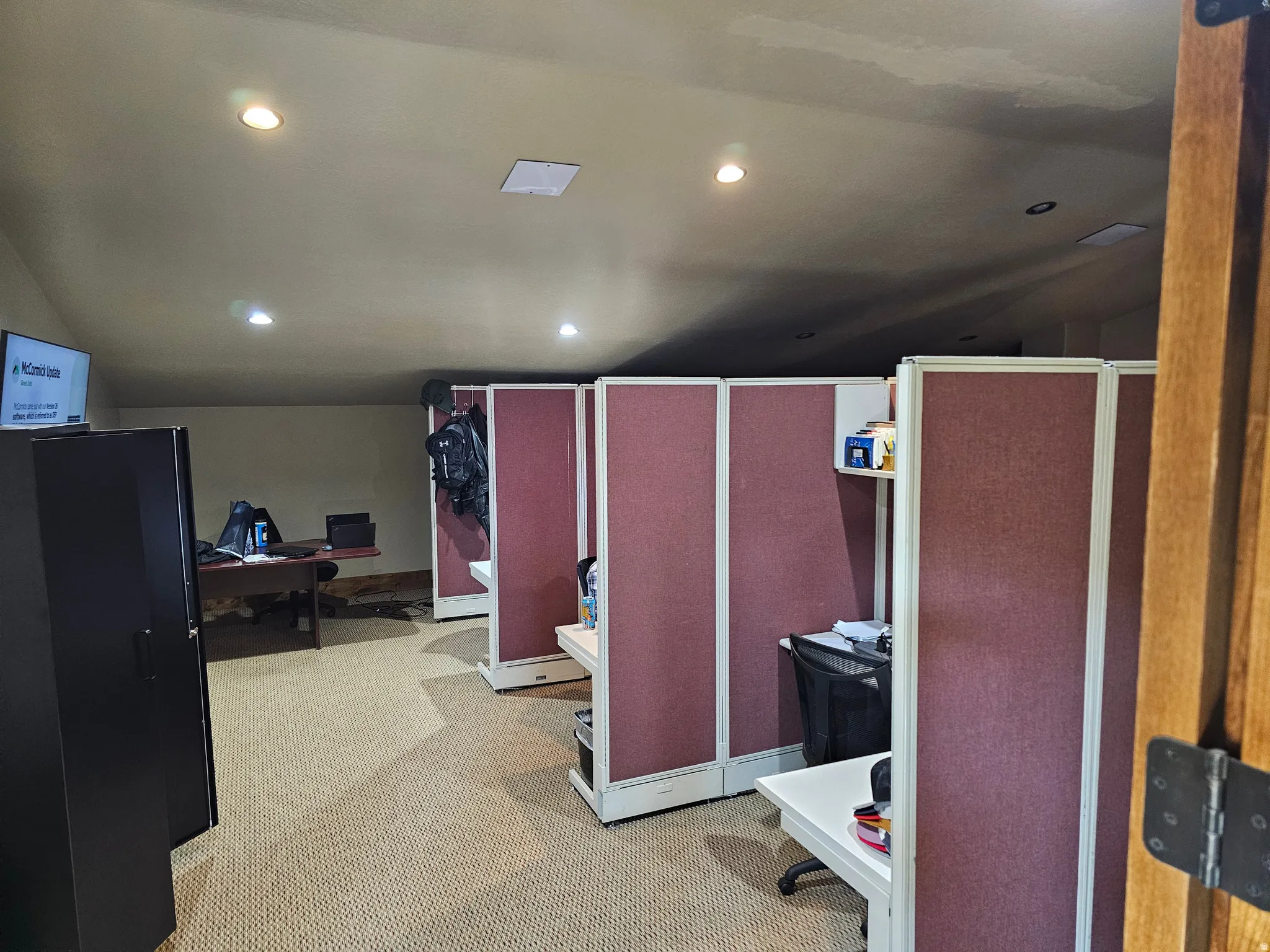Flexible workspace featuring individual cubicles with upholstered partitions, recessed lighting, and textured carpet flooring