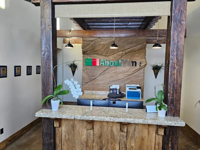 Reception desk featuring a stone countertop, wood-finish base, and exposed wood beams