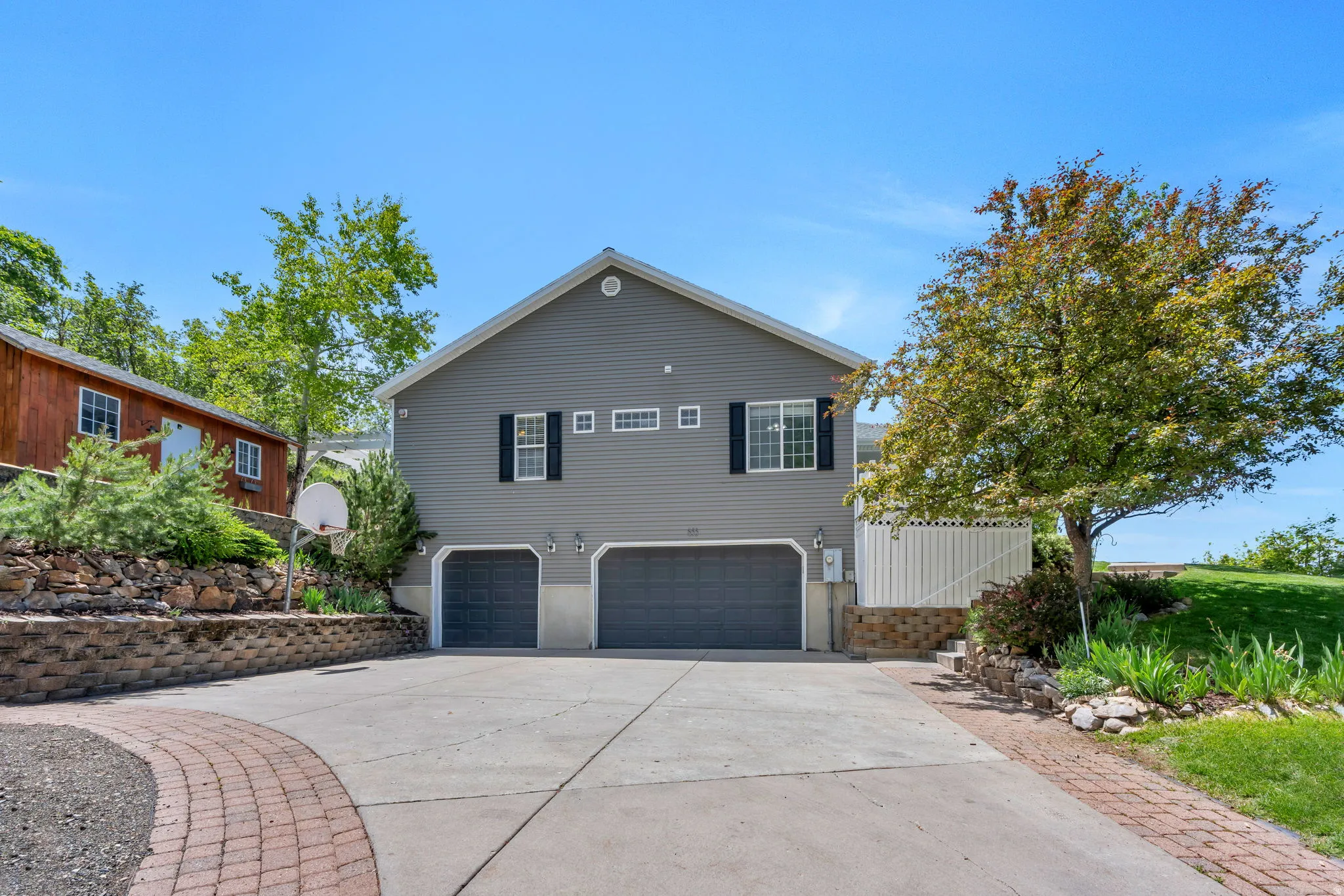 Two-car garage with paneled doors and exterior lighting, featuring gray siding and white window trim