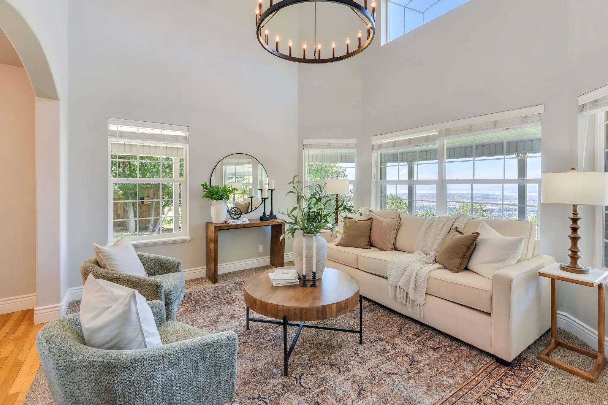 Two-story living area featuring a large chandelier, arched doorway, and abundant natural light from multiple windows