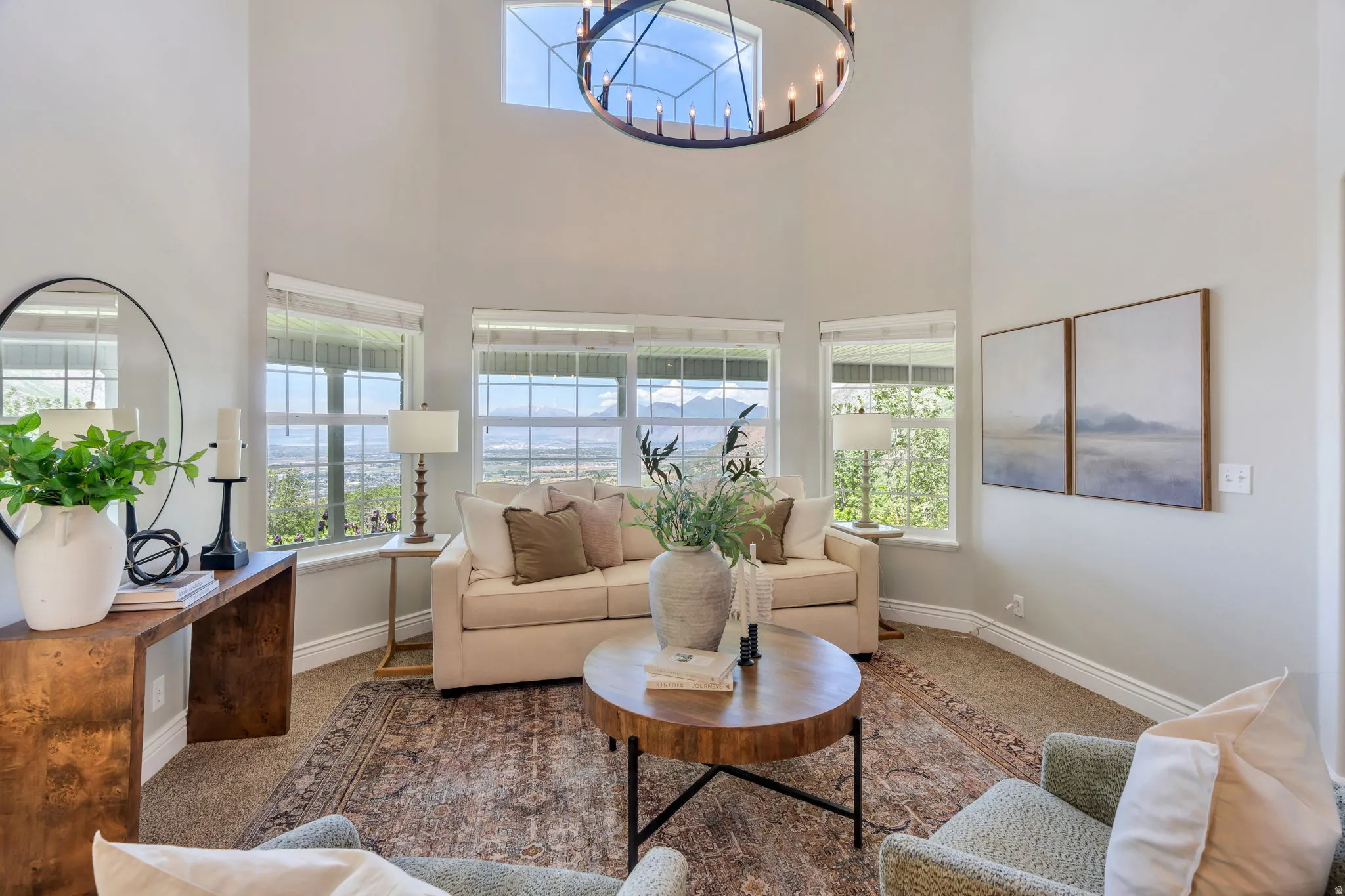 Great room featuring vaulted ceilings, a large circular chandelier, multiple windows, and light neutral wall colors