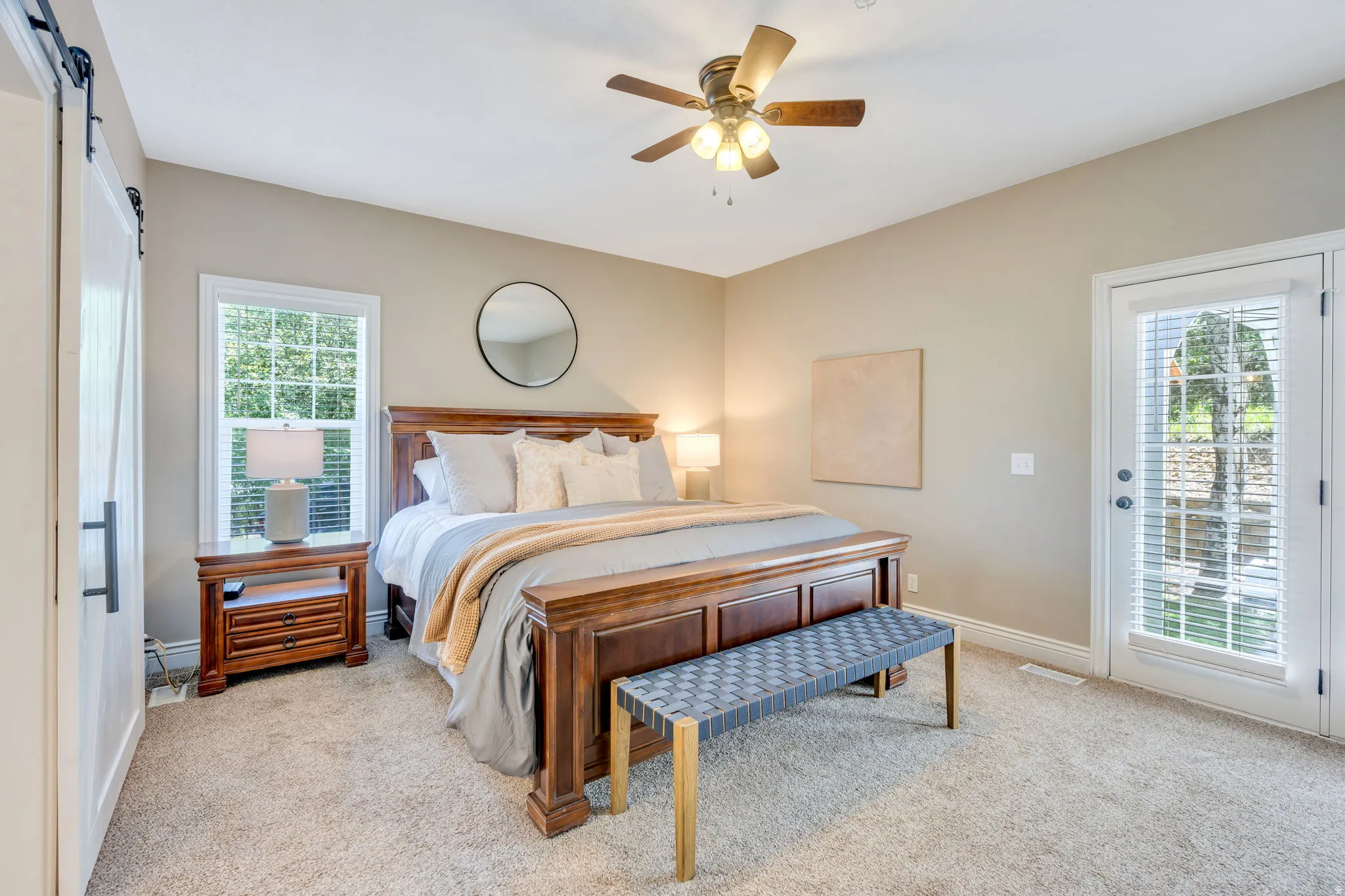 Carpeted room featuring a ceiling fan with integrated lighting, a sliding barn door, and a glass-paned exterior door with integrated blinds