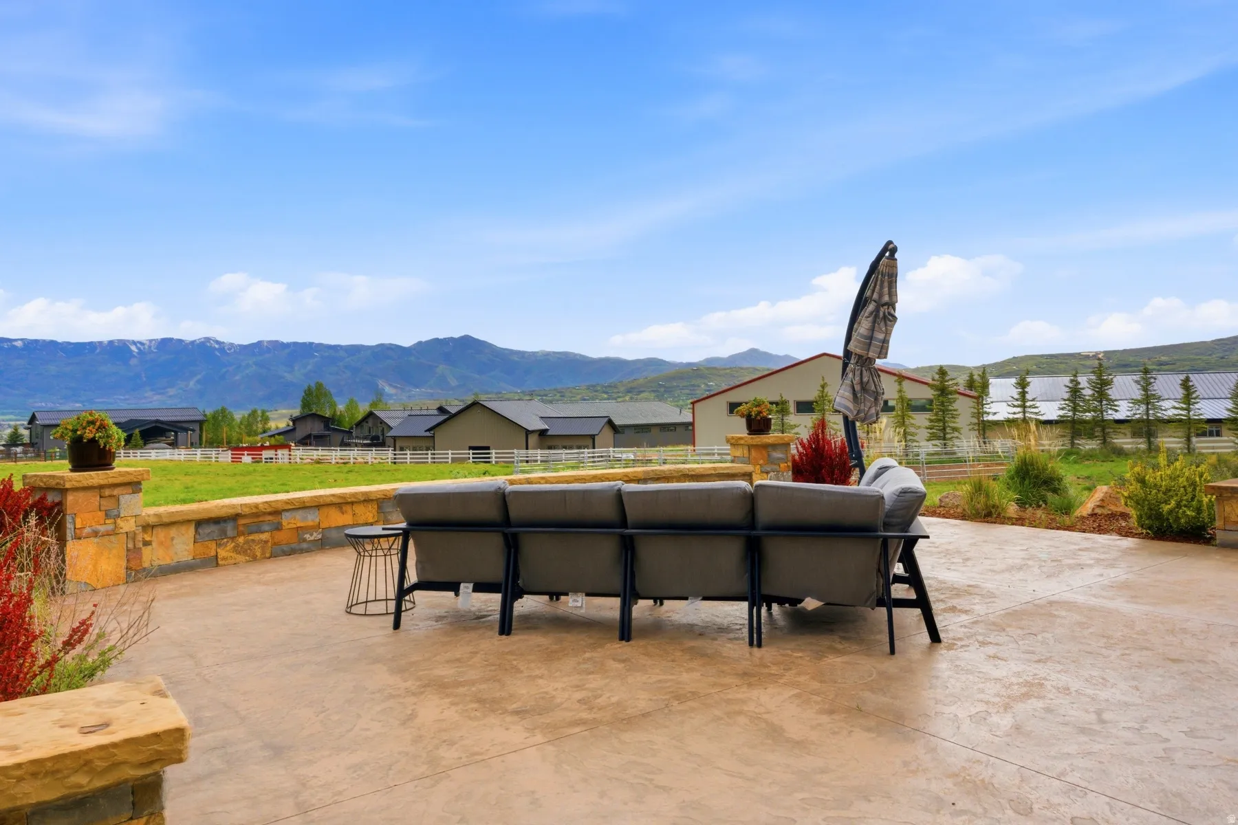 Expansive stamped concrete patio featuring a low stone retaining wall with matching pillars
