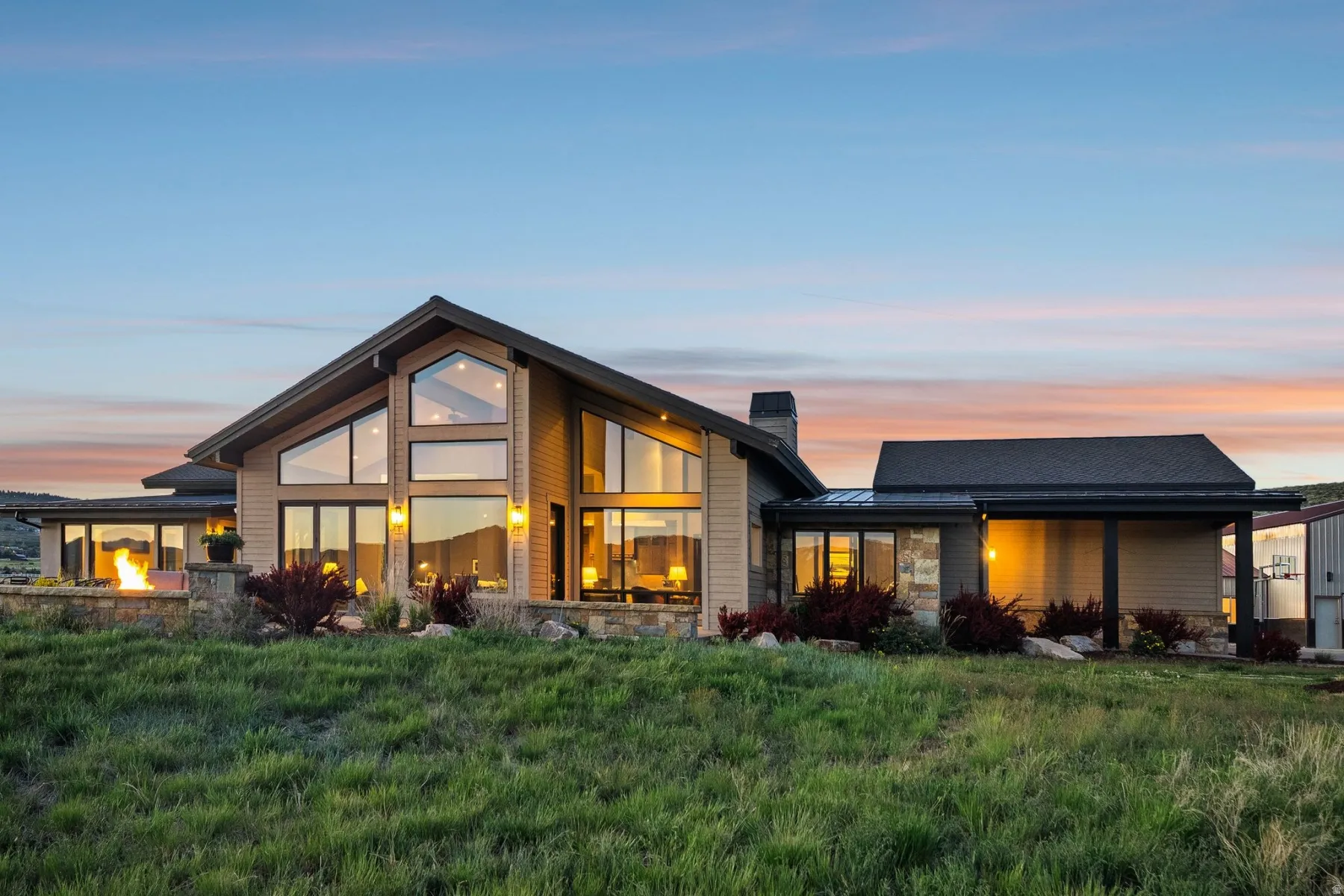 Contemporary architecture featuring a soaring A-frame roofline, extensive window walls, stacked stone accents, and a covered entry