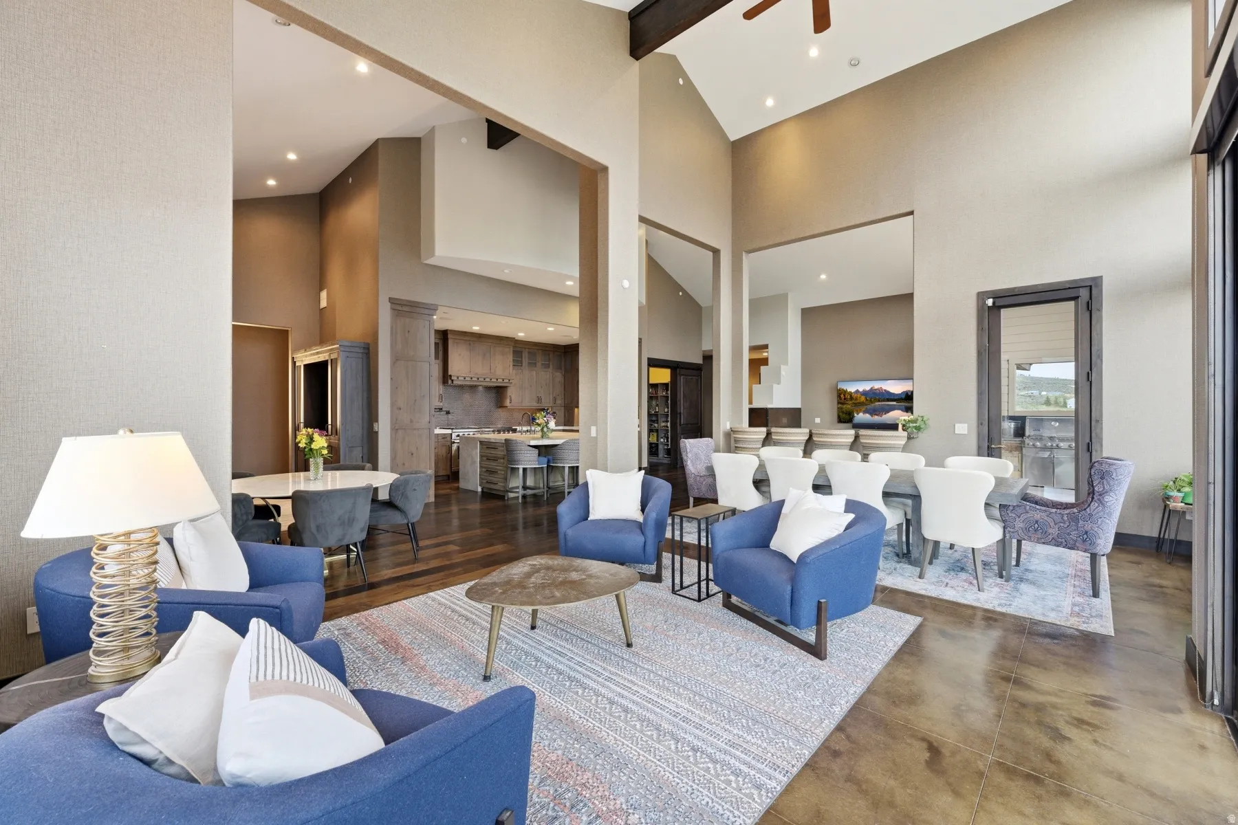 Vaulted ceilings with exposed beams, recessed lighting, expansive glass doors, wood-finish flooring, and a kitchen with an island