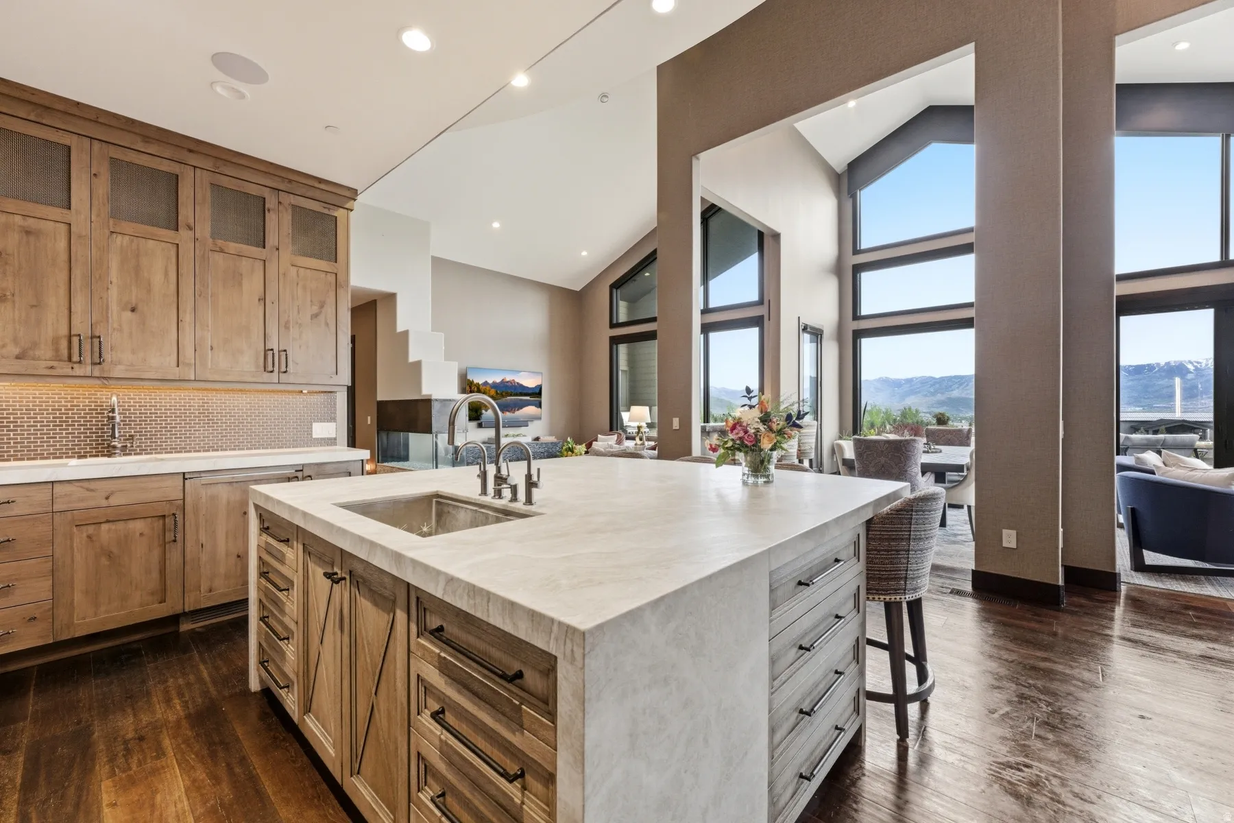 Expansive kitchen island with an integrated stainless steel sink and industrial-style faucet, complemented by wood-finish flooring