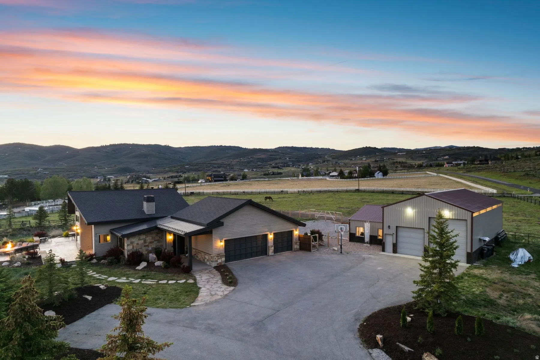 Contemporary residence featuring stone and siding exterior, an attached two-car garage, and a paved driveway
