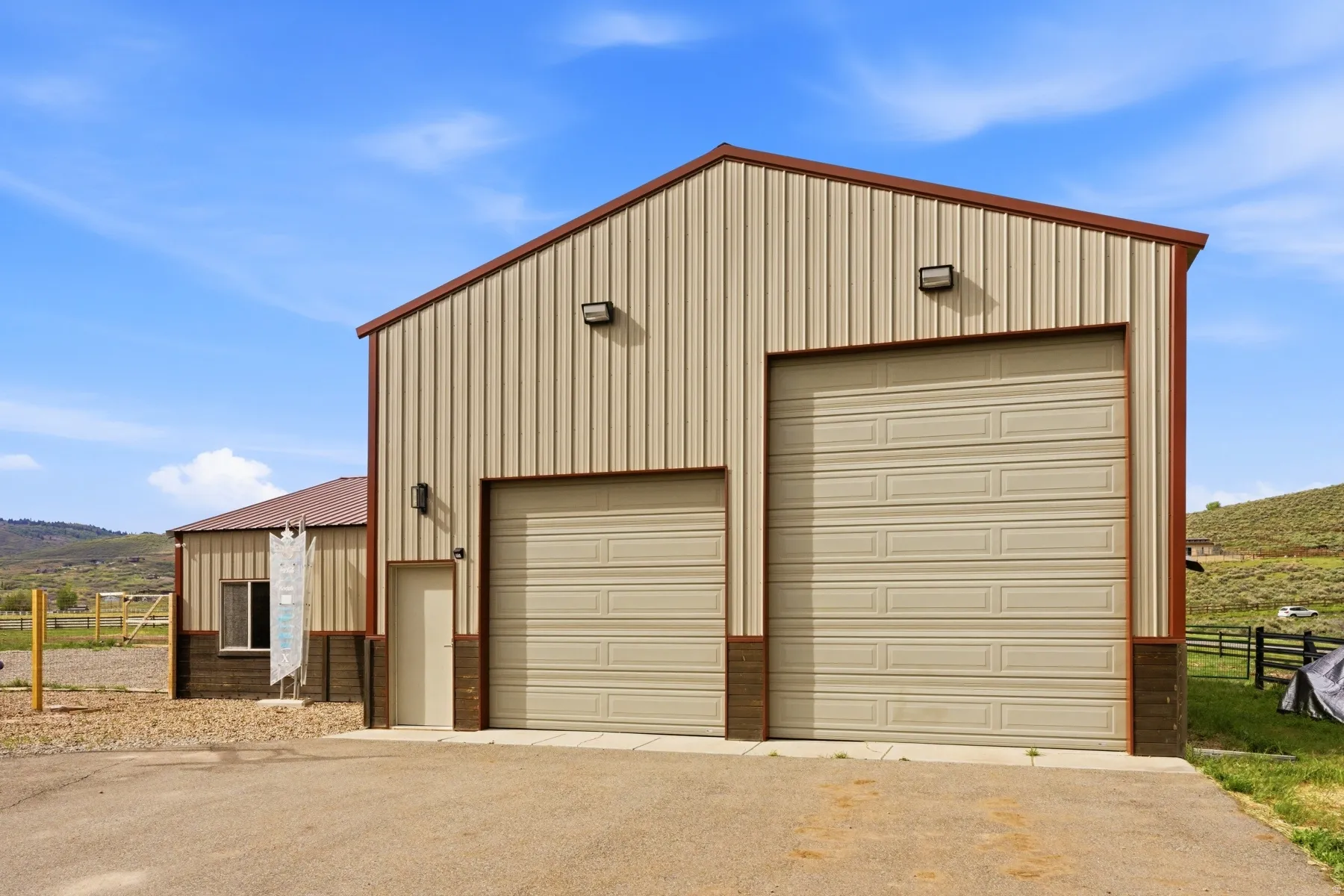 Large utility building featuring two roll-up garage doors, a pedestrian entry door, and exterior lighting fixtures