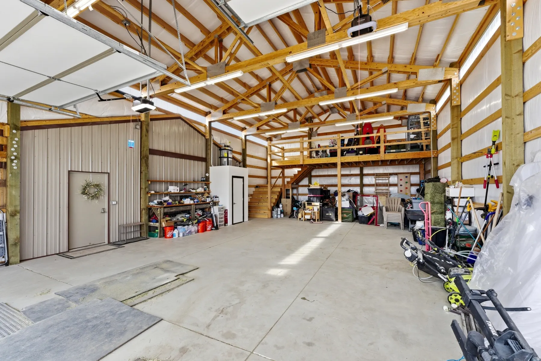Spacious utility building featuring a concrete floor, exposed wood beam ceiling, and metal siding