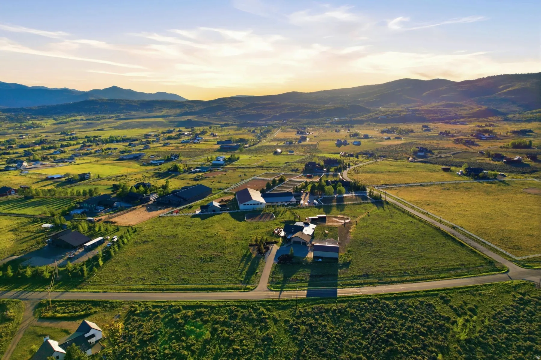 Expansive property featuring multiple structures, open green spaces, and a paved private road
