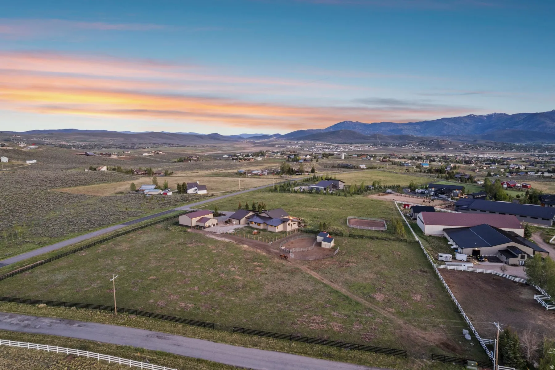 Expansive rural property featuring multiple structures, a fenced arena, and a large open field