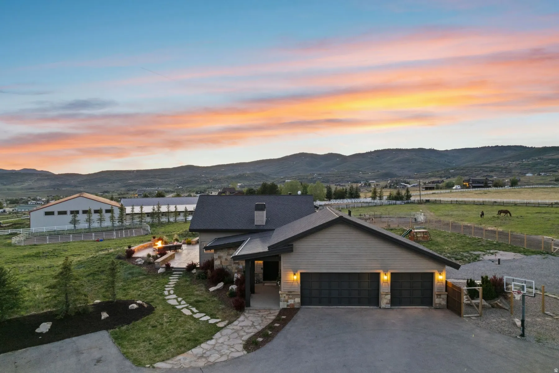 Modern-style home featuring a two-car garage with carriage-style doors, stone and siding exterior, and an expansive stone patio with built-in seating