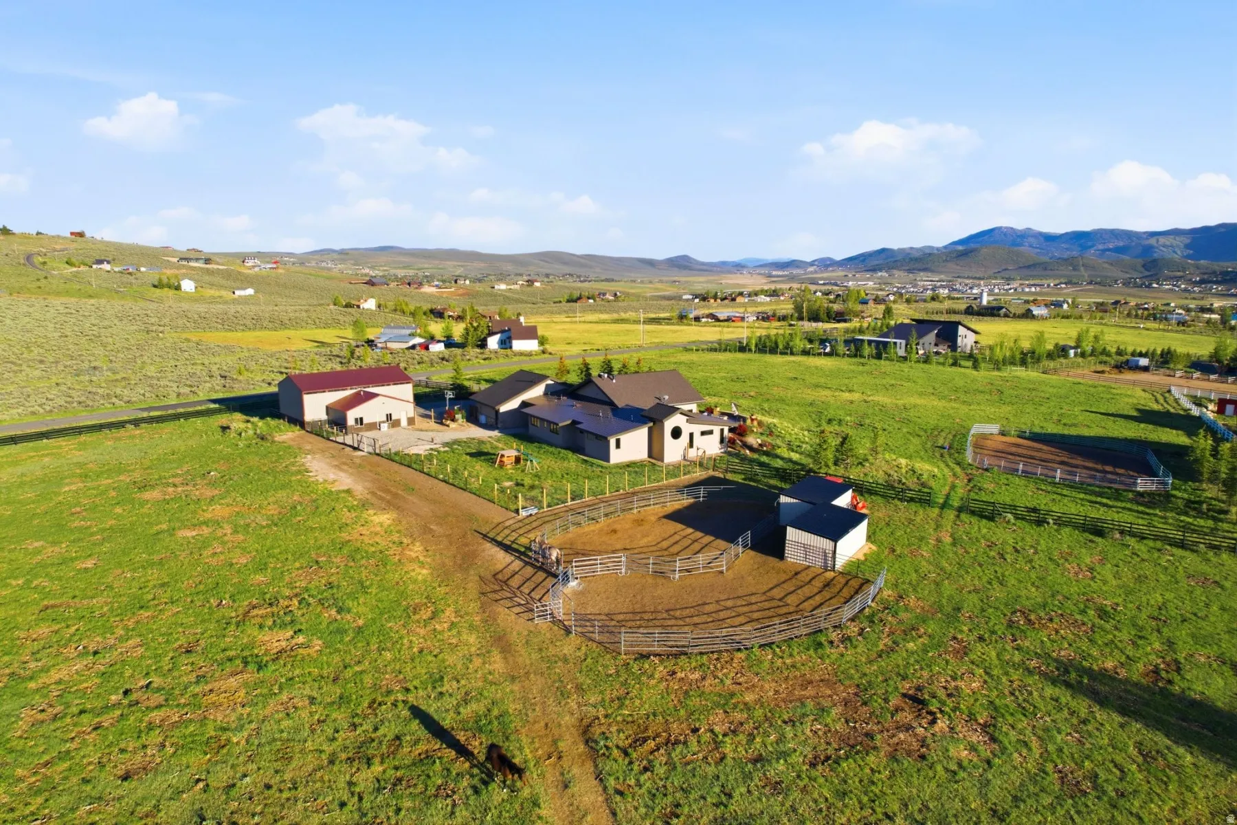 Expansive property featuring multiple structures, including a primary residence, a large barn with a red roof, and smaller outbuildings
