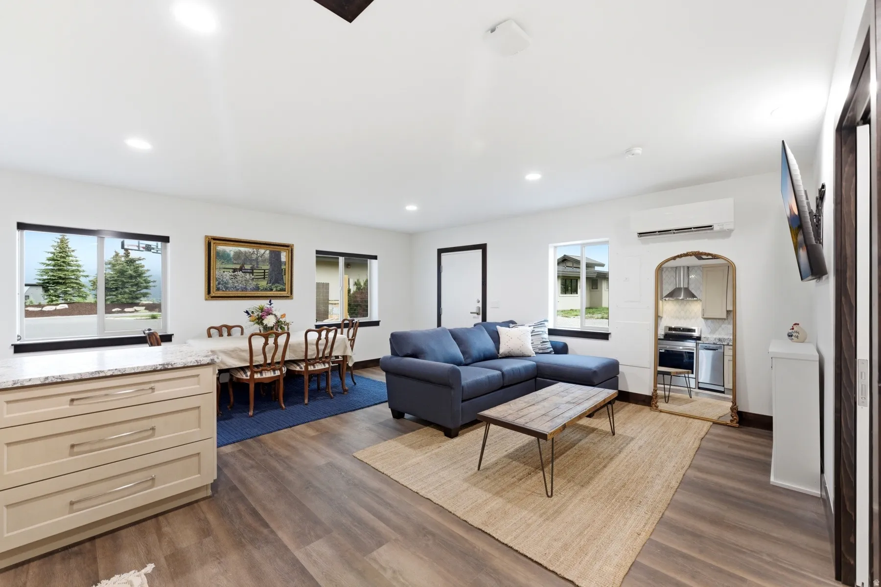 Open-concept living space featuring wood-finish flooring, recessed lighting, and multiple windows