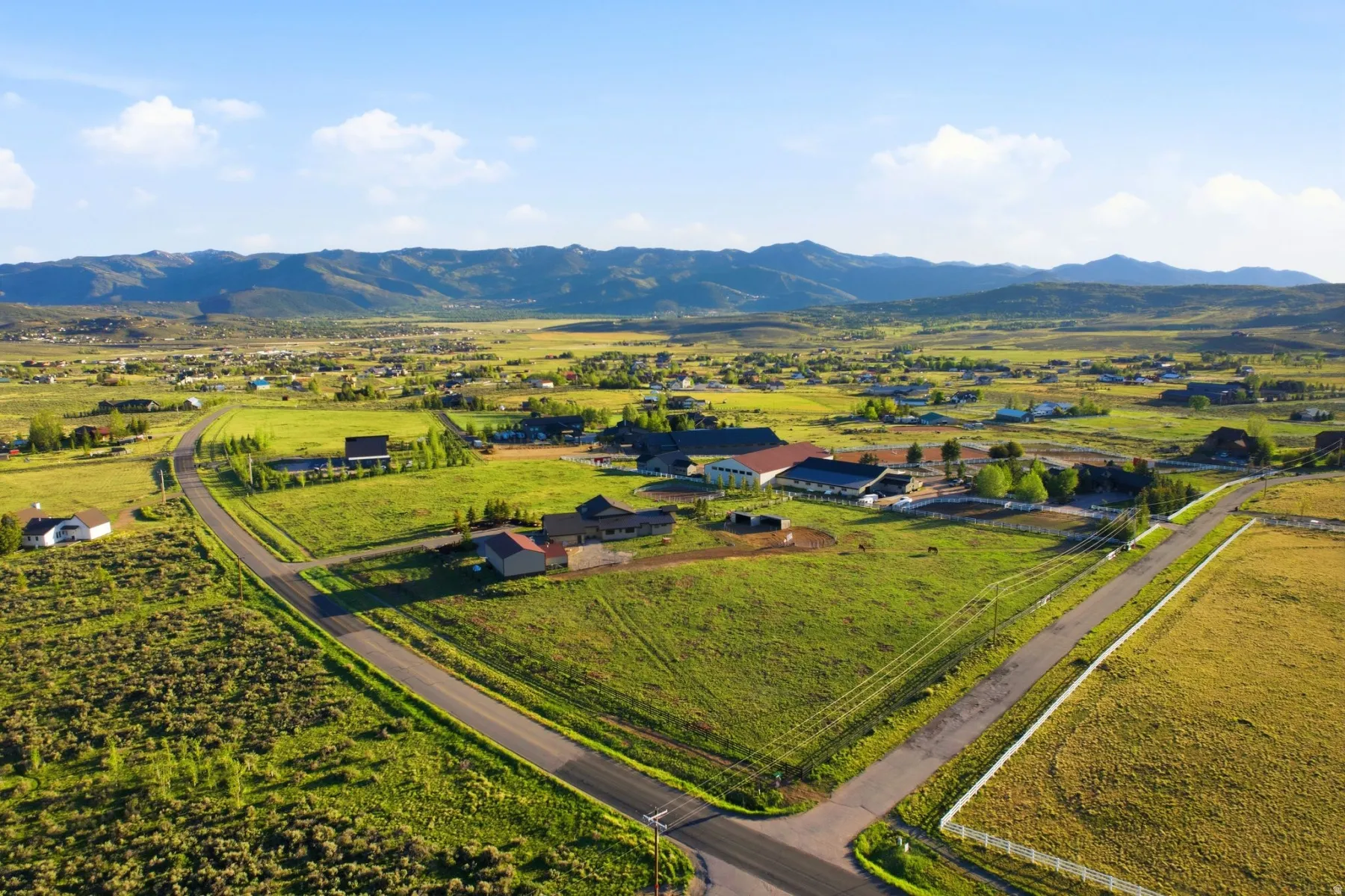 Expansive property featuring verdant green fields, multiple structures, and paved roads