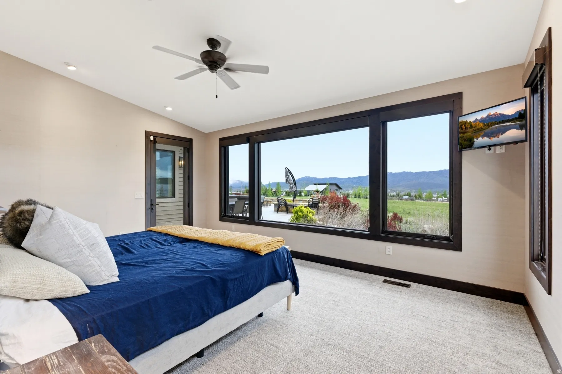Expansive window wall with dark trim framing distant mountains and green fields