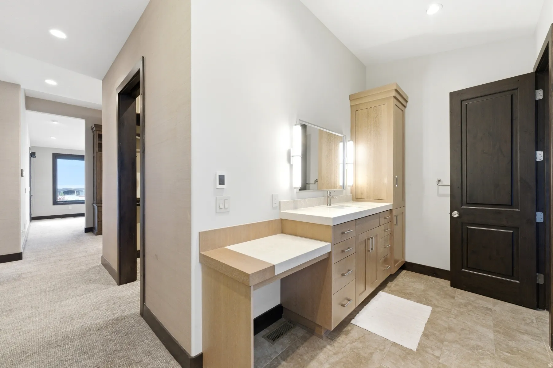 Vanity area featuring a light wood-finish cabinetry, integrated sink, and illuminated mirror