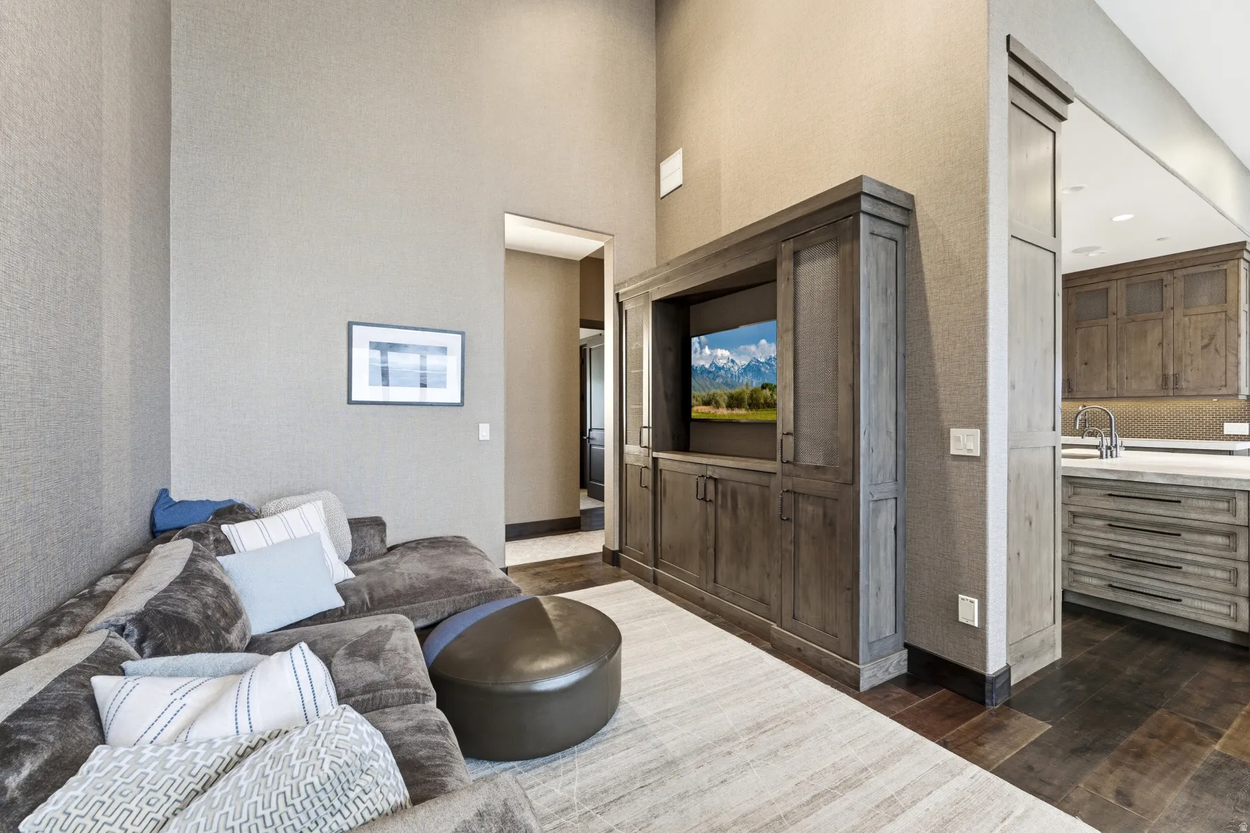 Living area featuring a custom built-in entertainment center, high ceilings, textured wall coverings, and dark wood-finish flooring