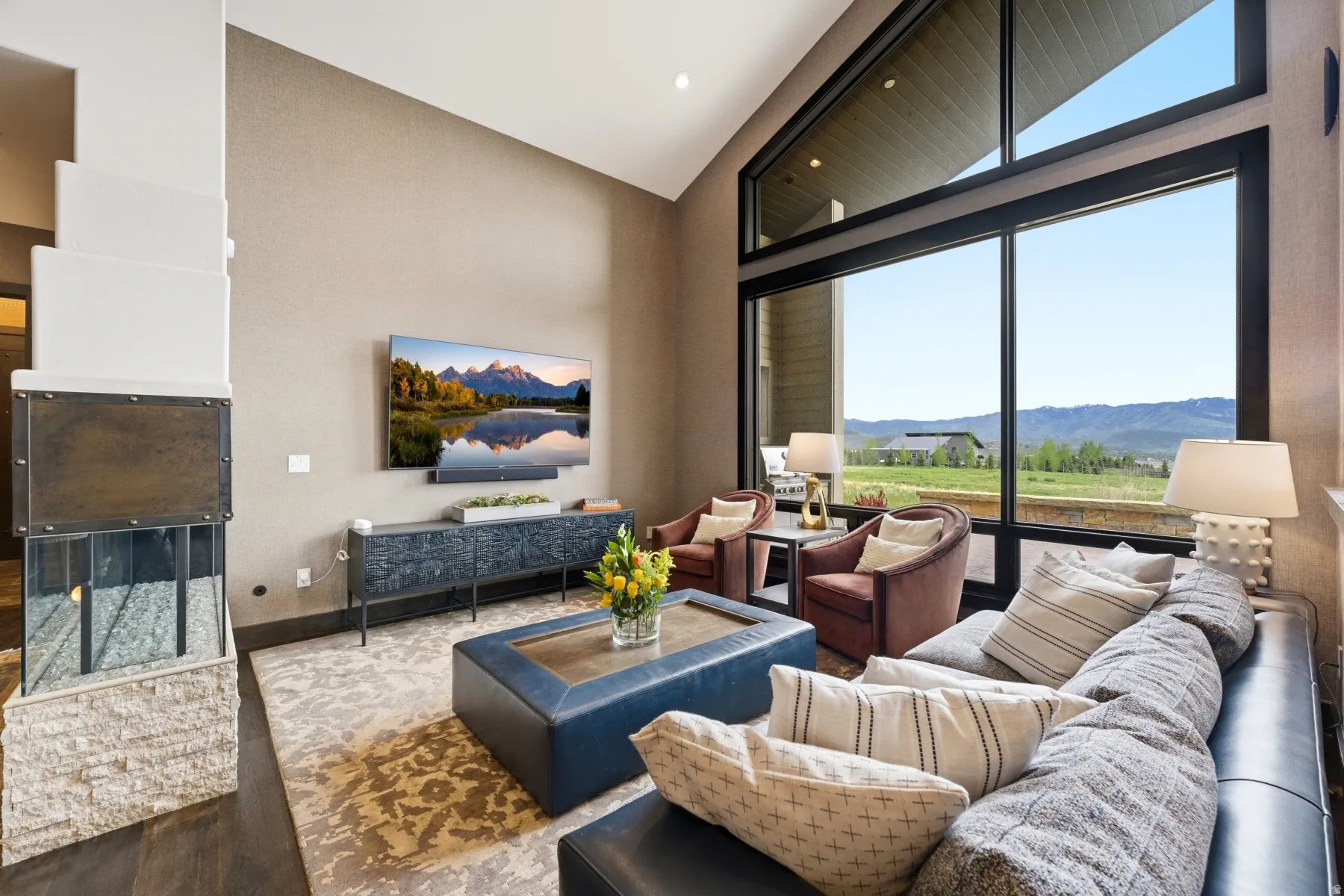Spacious living area featuring a vaulted ceiling and expansive floor-to-ceiling windows