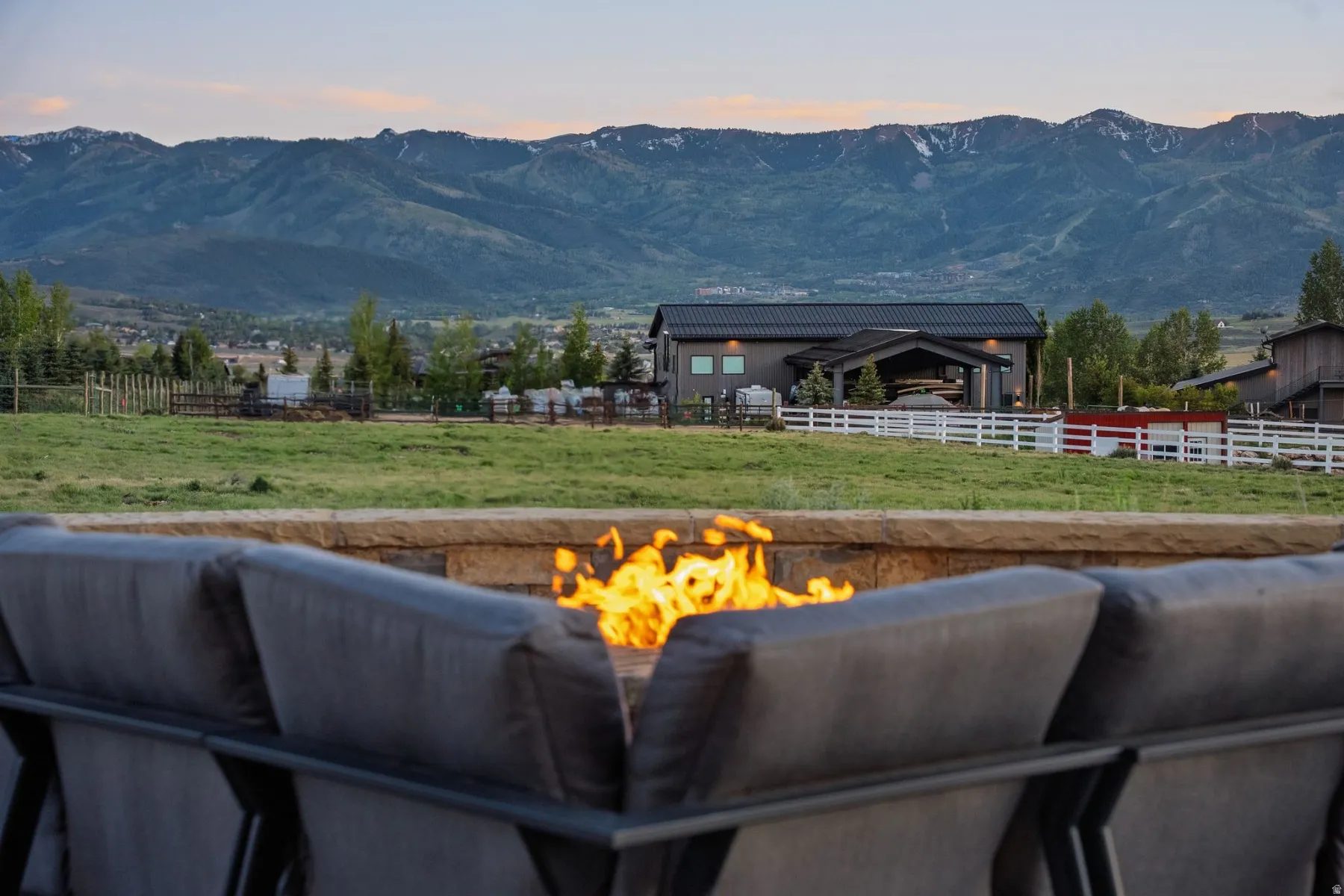 Stone-clad fire pit with a broad capstone, surrounded by outdoor seating
