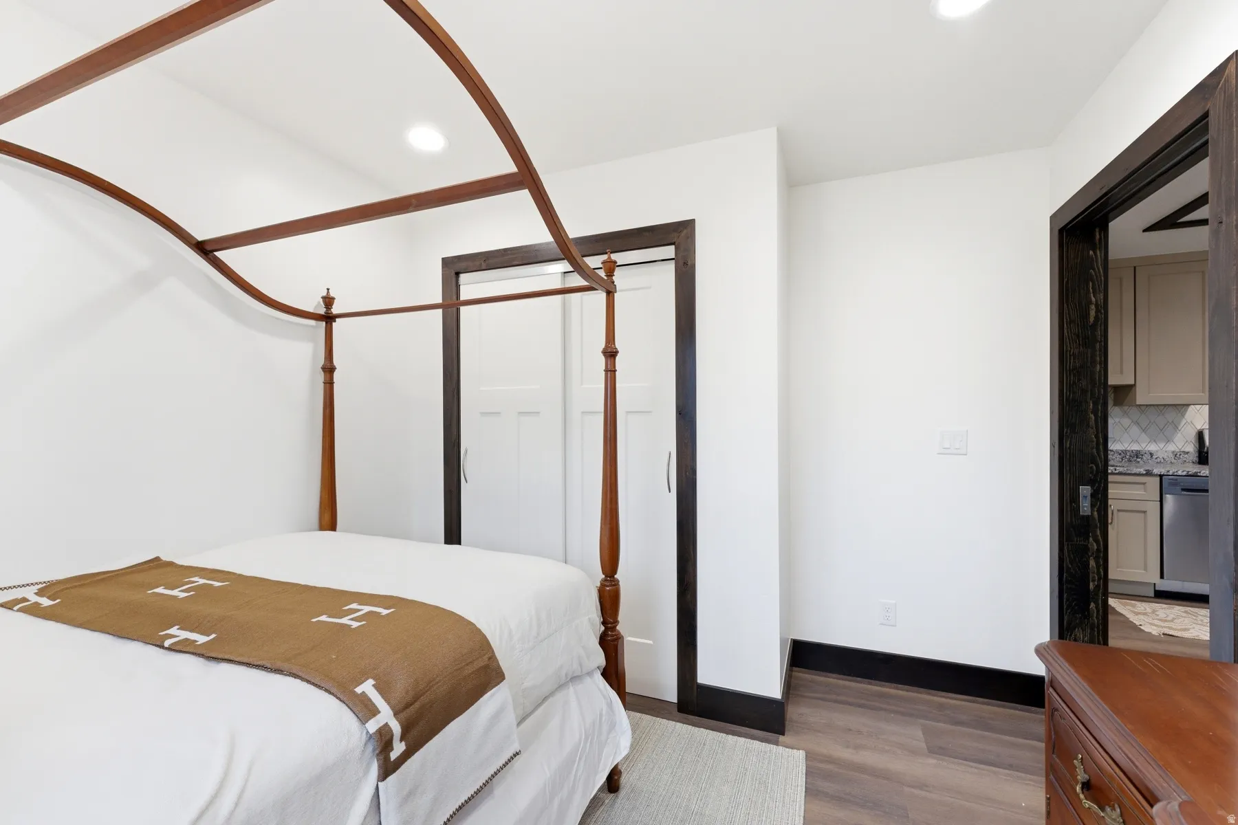 Recessed lighting illuminates this space featuring wood-finish flooring and crisp white walls