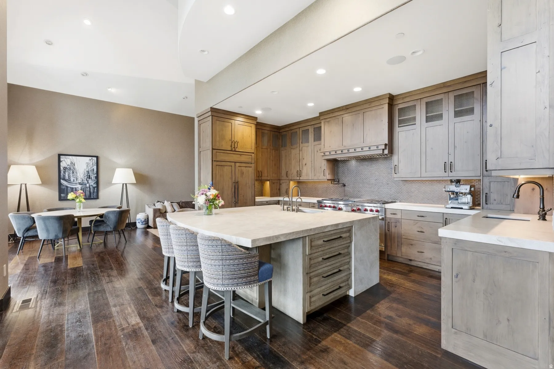 Spacious kitchen featuring warm wood-finish cabinetry, a large center island with countertop seating, stainless steel range, and stone countertops